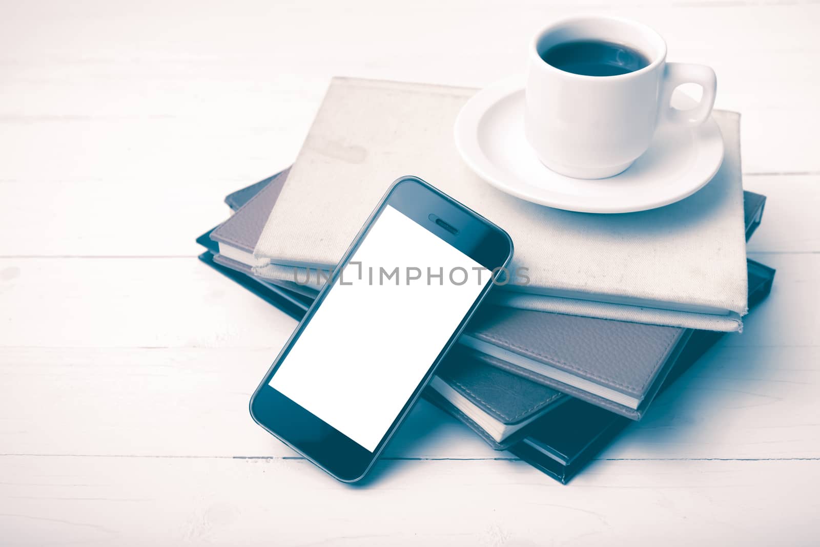 coffee cup with phone and stack of book on white wood table vintage style