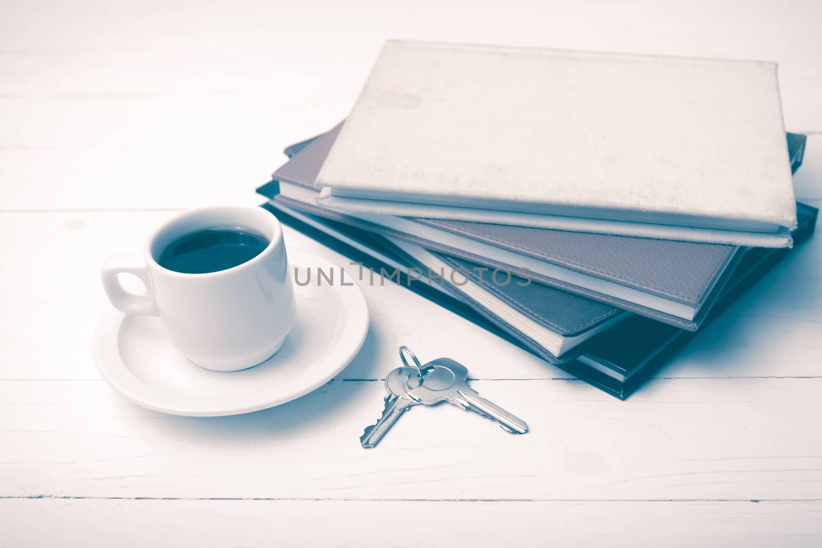 coffee cup,key and stack of book on white wood table vintage style
