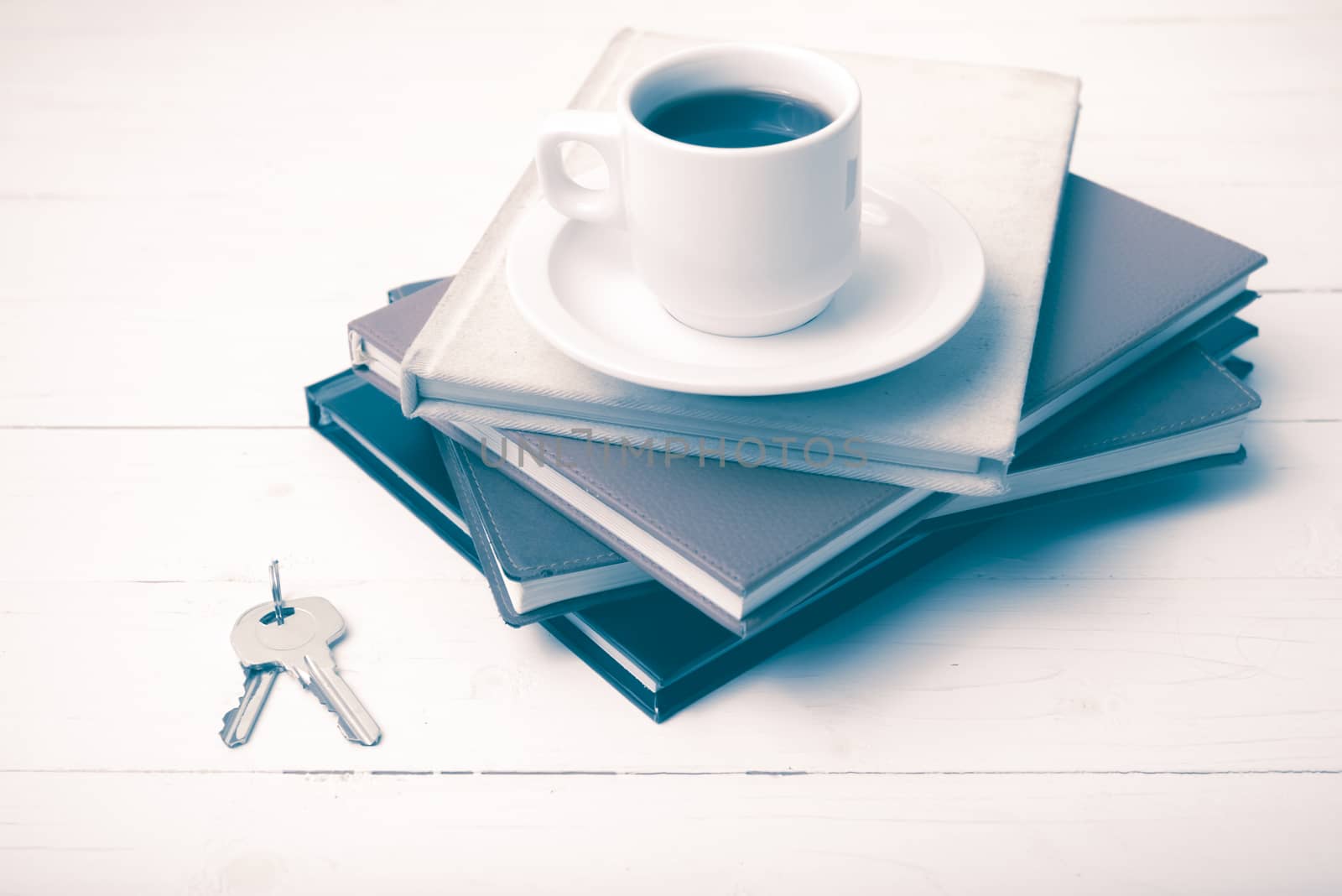 coffee cup,key and stack of book on white wood table vintage style