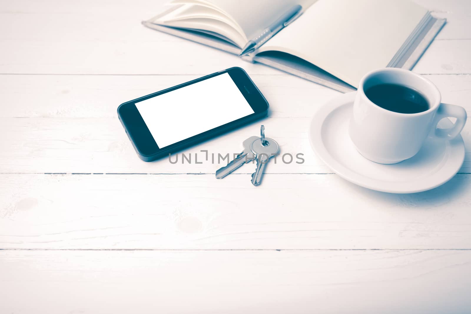 coffee cup with phone, key and open notebook on white wood table vintage style