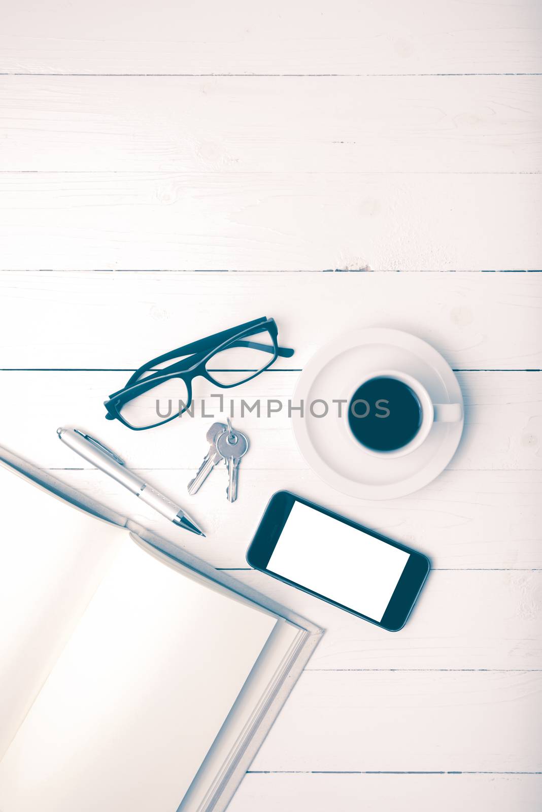 coffee cup with phone, key,eyeglasses and open notebook on white wood table vintage style