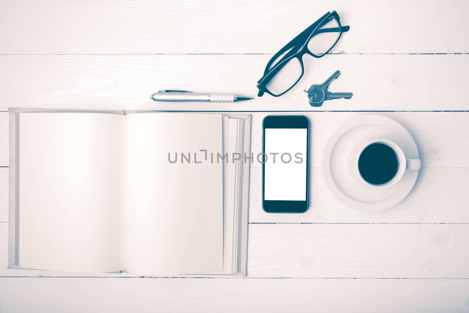 coffee cup with phone, key,eyeglasses and open notebook on white wood table vintage style