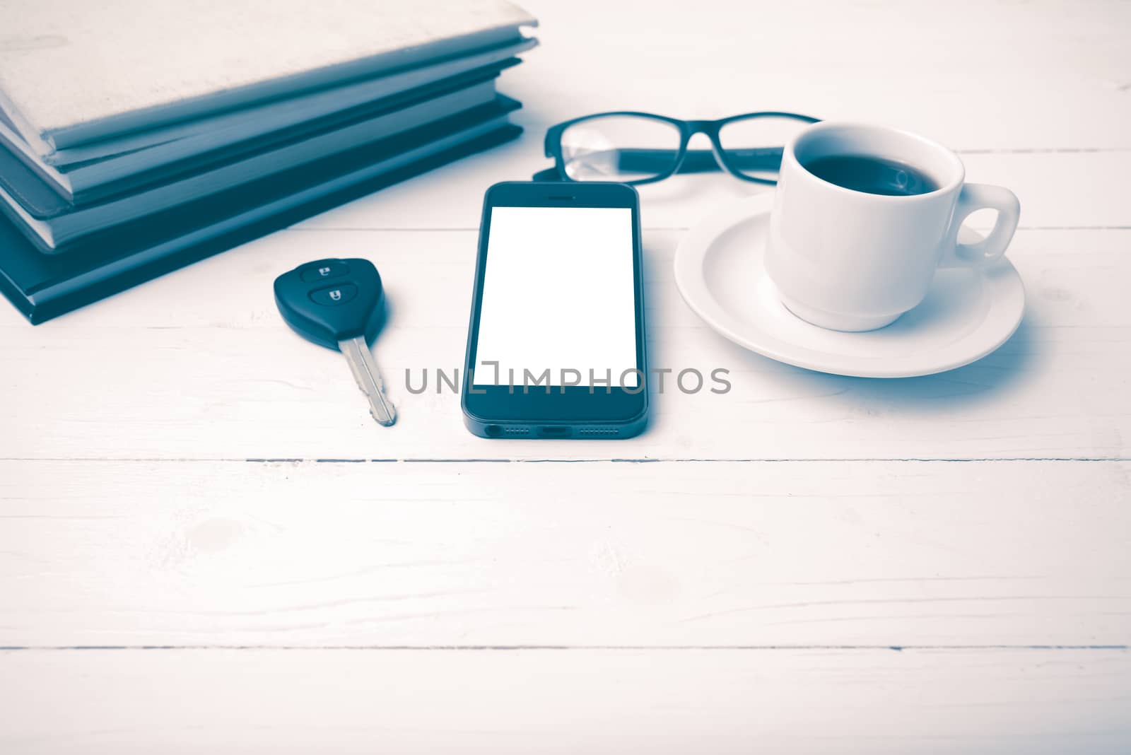coffee cup with phone, car key,eyeglasses and stack of book on white wood table vintage style