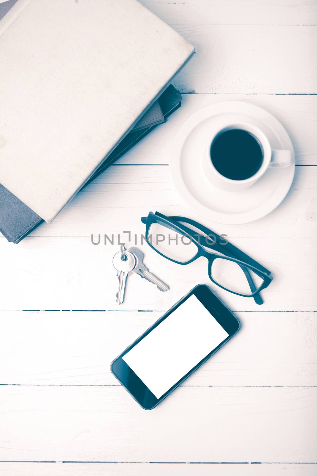 coffee cup with phone,key,eyeglasses and stack of book on white wood table vintage style