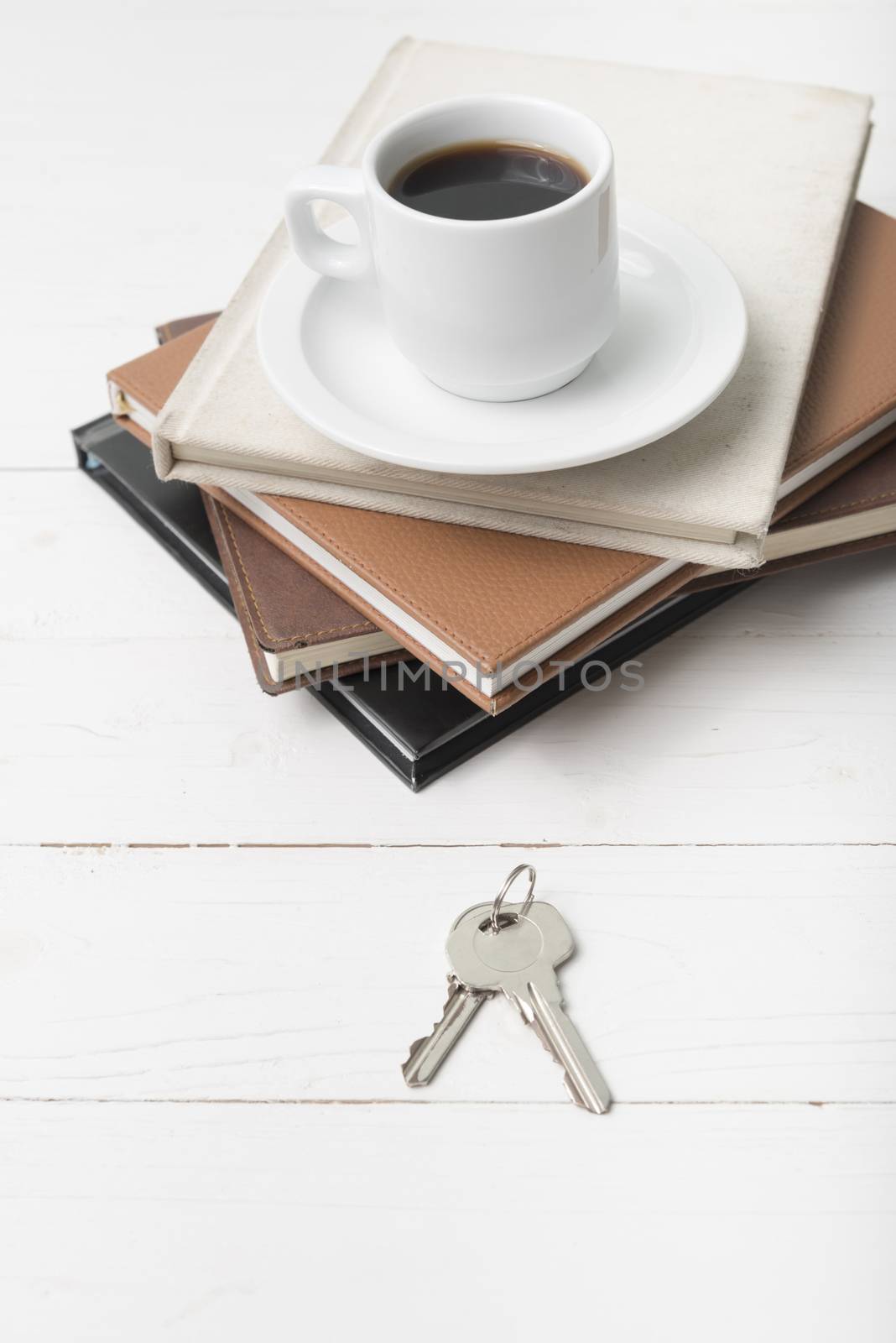 coffee cup,key and stack of book on white wood table