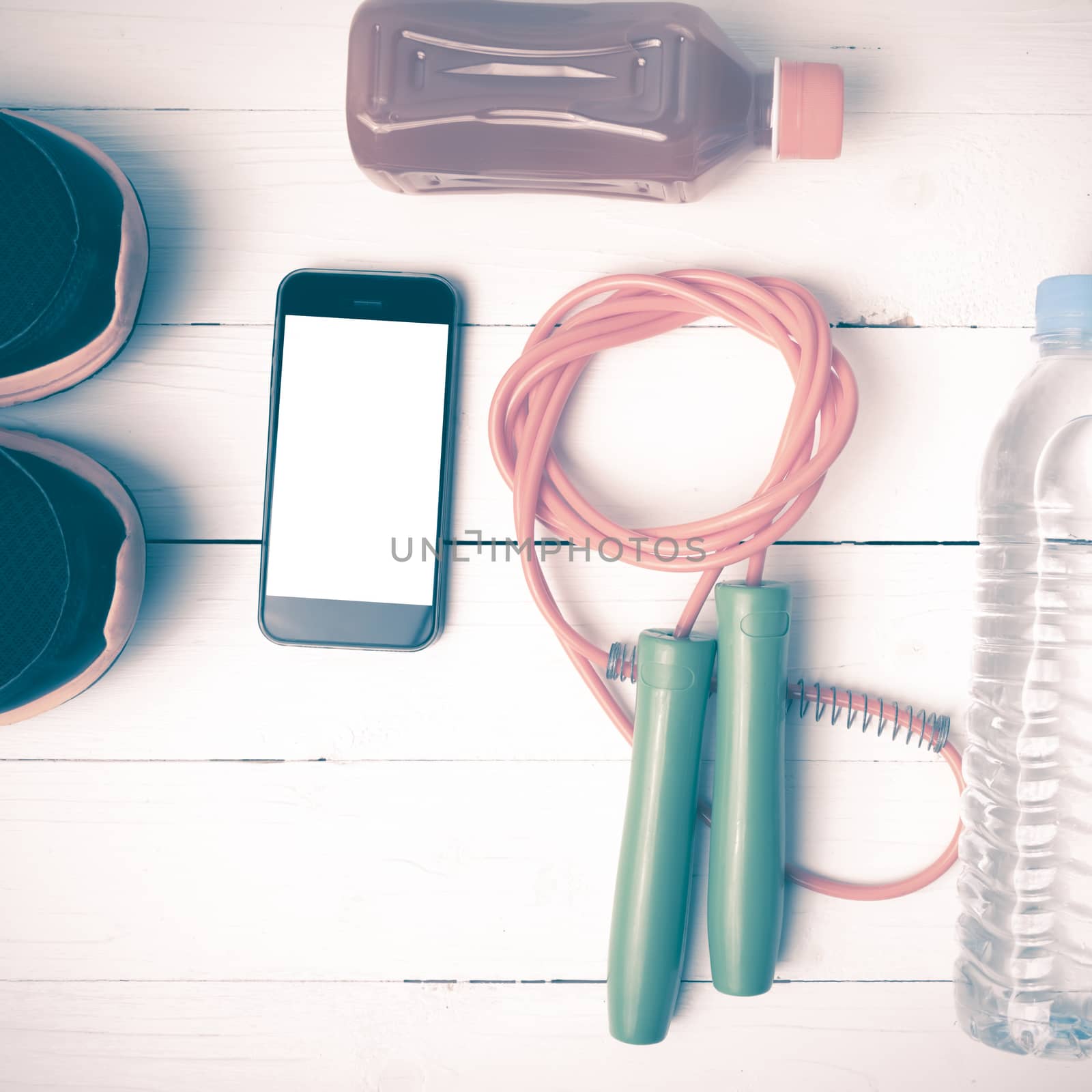 fitness equipment : running shoes,jumping rope,water,juice and phone on white wood background vintage style