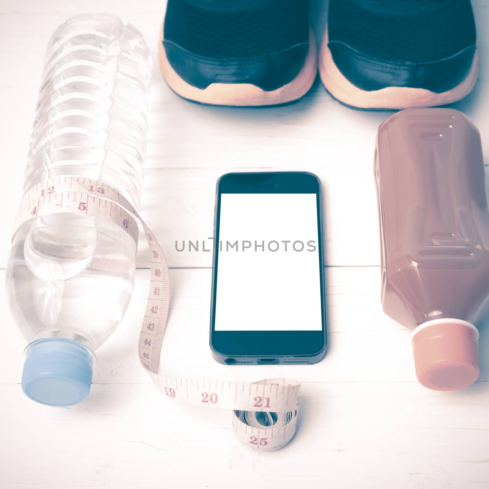 fitness equipment:running shoes,measuring tape,water,juice and phone on white wood background vintage style