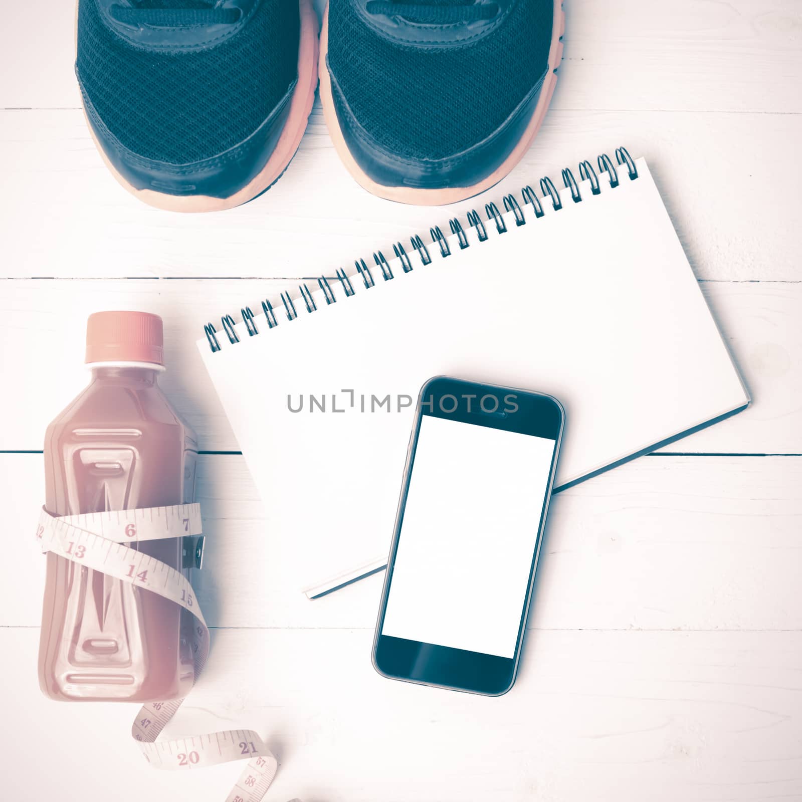 fitness equipment:running shoes,juice,measuring tape,notepad and phone on white wood background vintage style