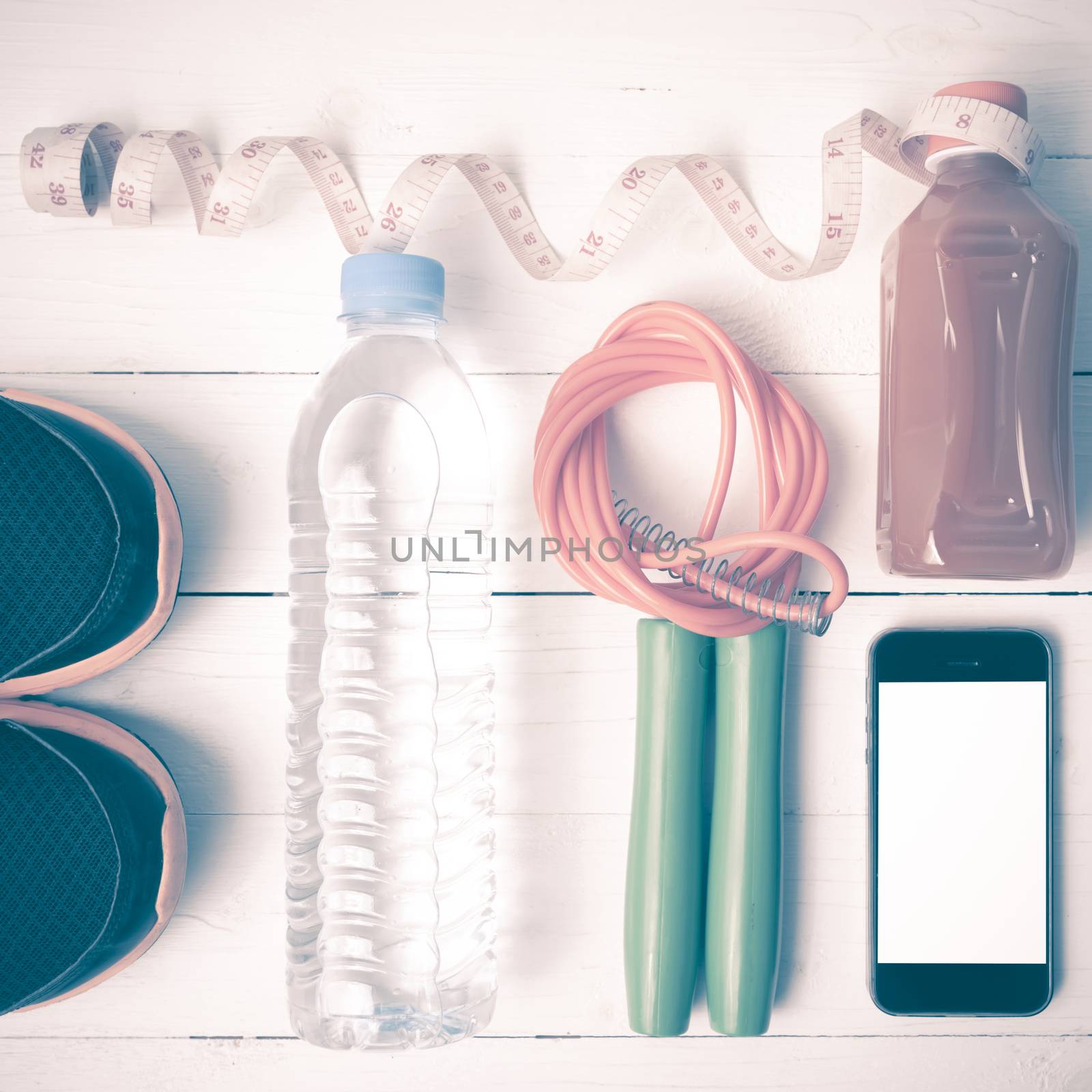 fitness equipment:running shoes,phone,measuring tape,water,juice and jumpong rope on white wood background vintage style