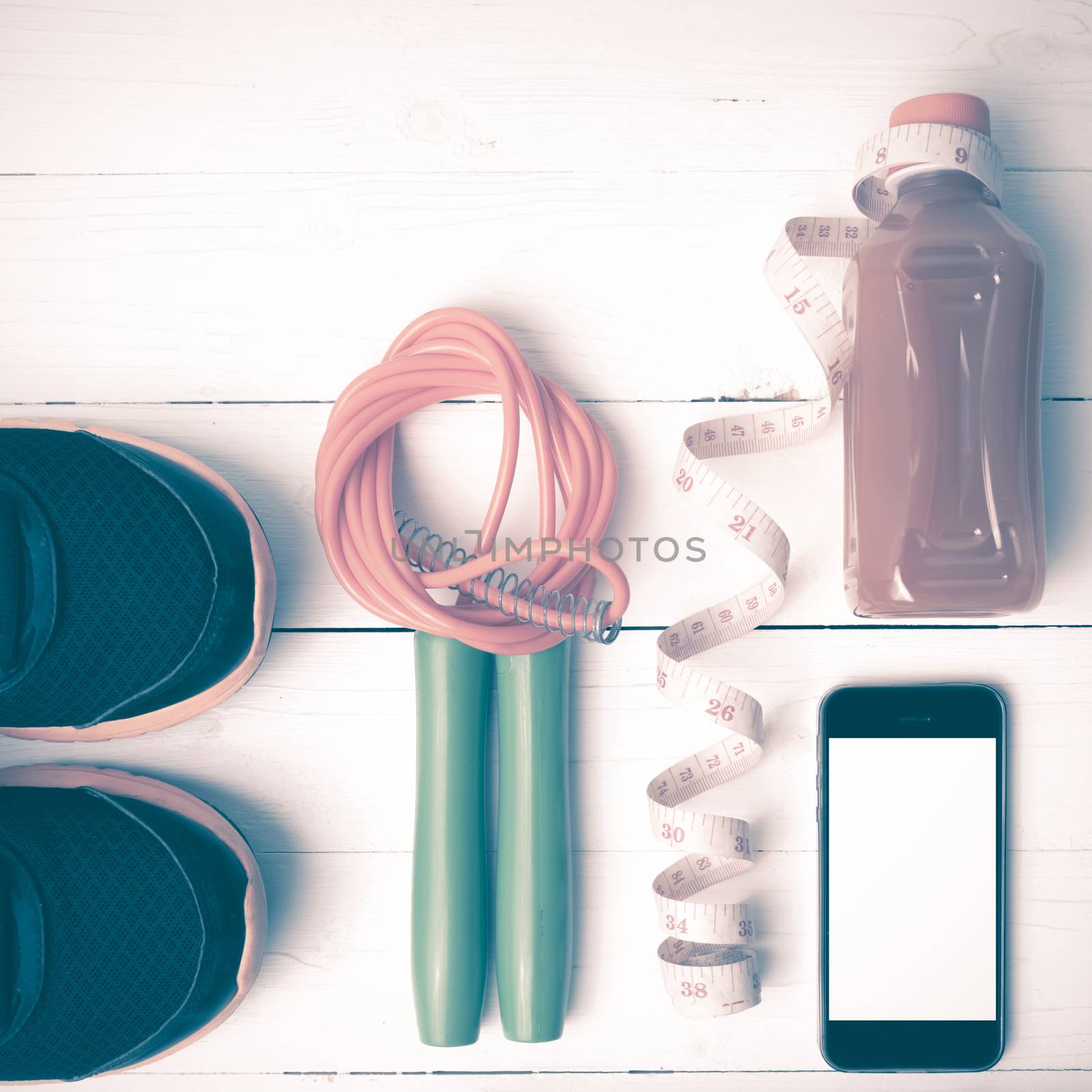 fitness equipment:running shoes,phone,measuring tape,water,juice and jumpong rope on white wood background vintage style