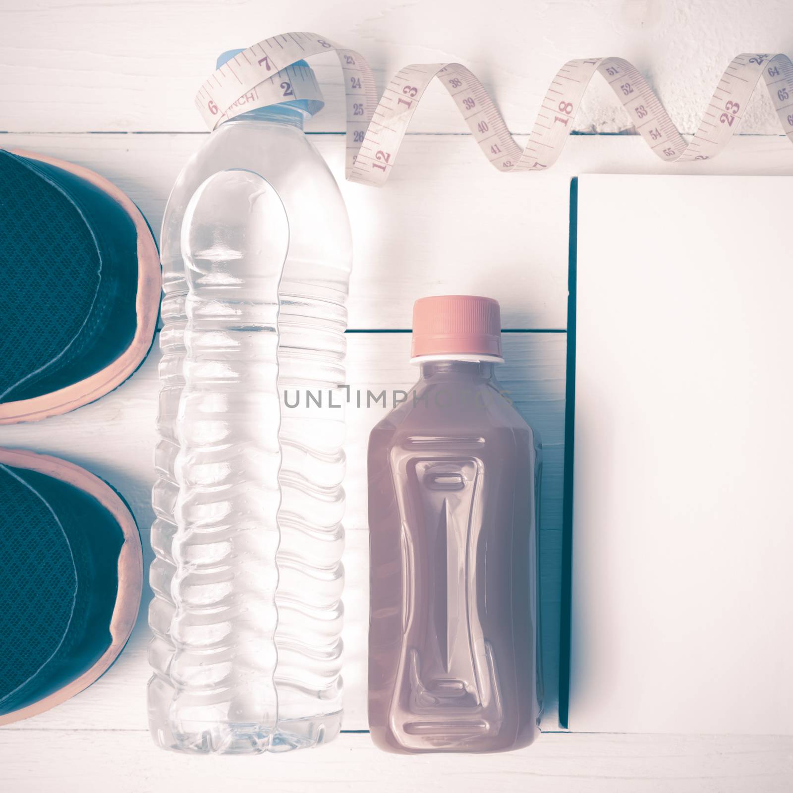 fitness equipment:running shoes,water,measuring tape,notepad,phone and juice on white wood background vintage style