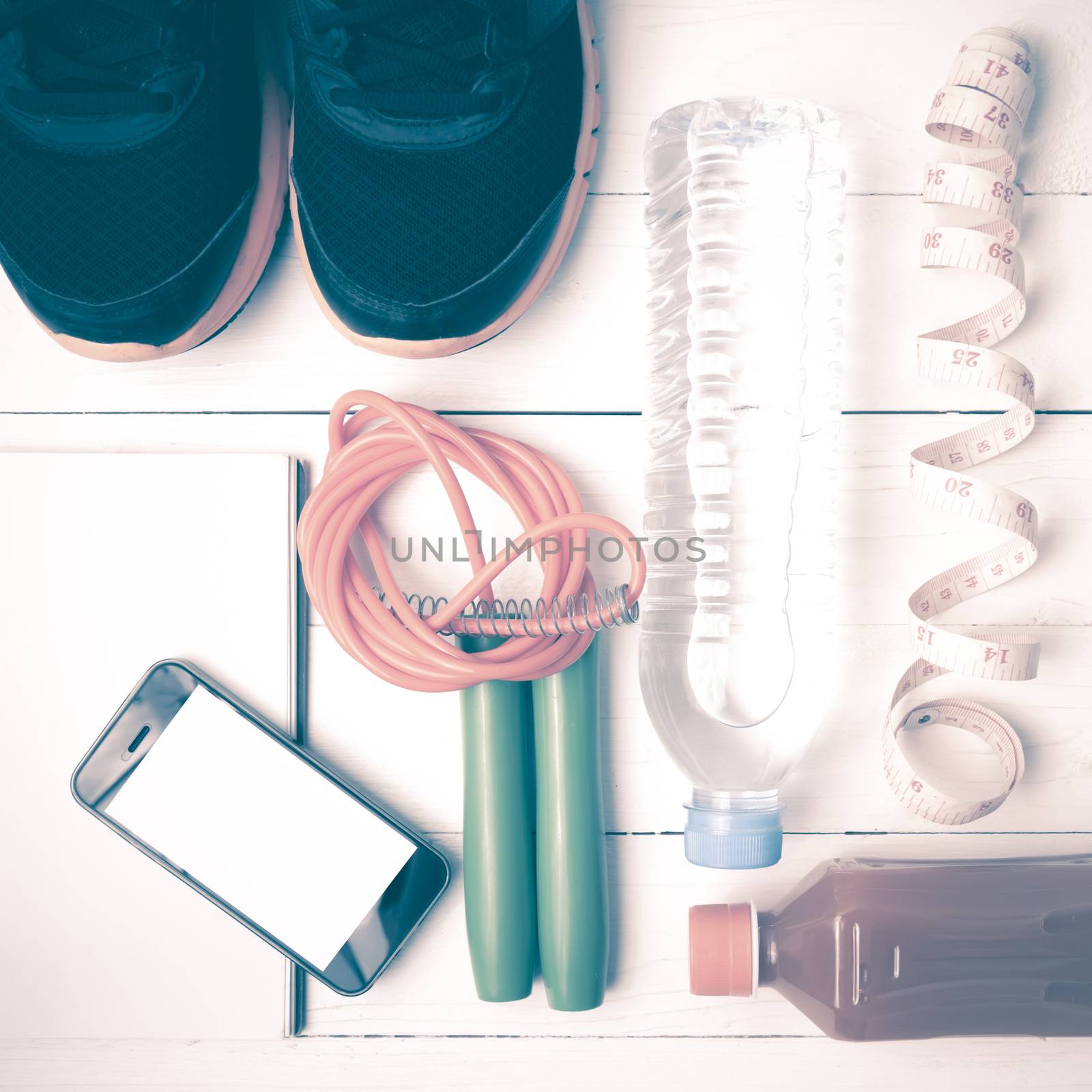 fitness equipment:running shoes,jumping rope,notepad,phone,water,juice and measuring tape on white wood background vintage style