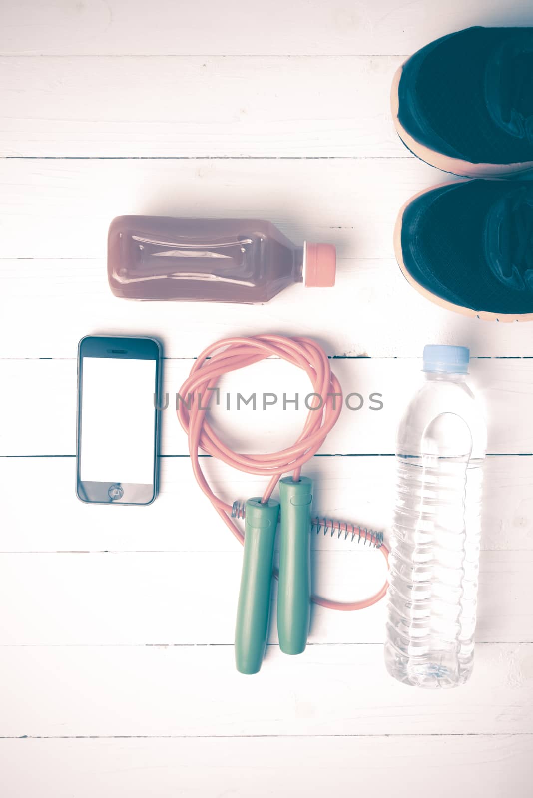 fitness equipment : running shoes,jumping rope,water,juice and phone on white wood background vintage style