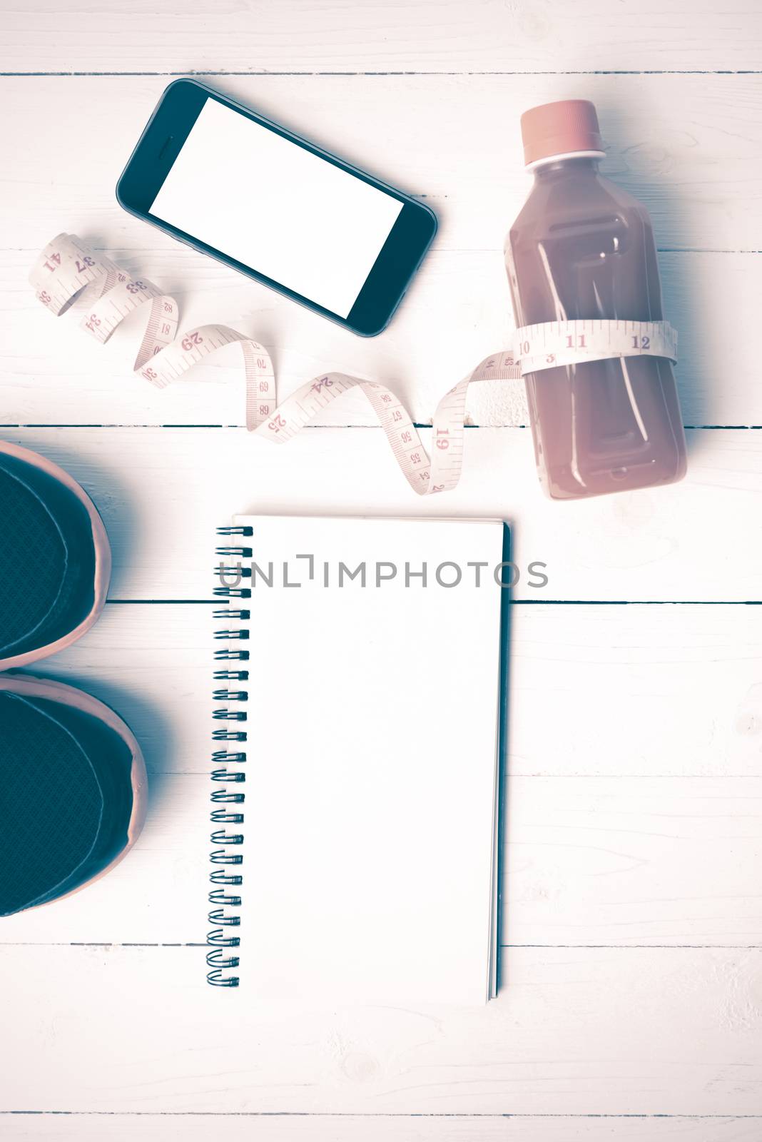 fitness equipment:running shoes,juice,measuring tape,notepad and phone on white wood background vintage style