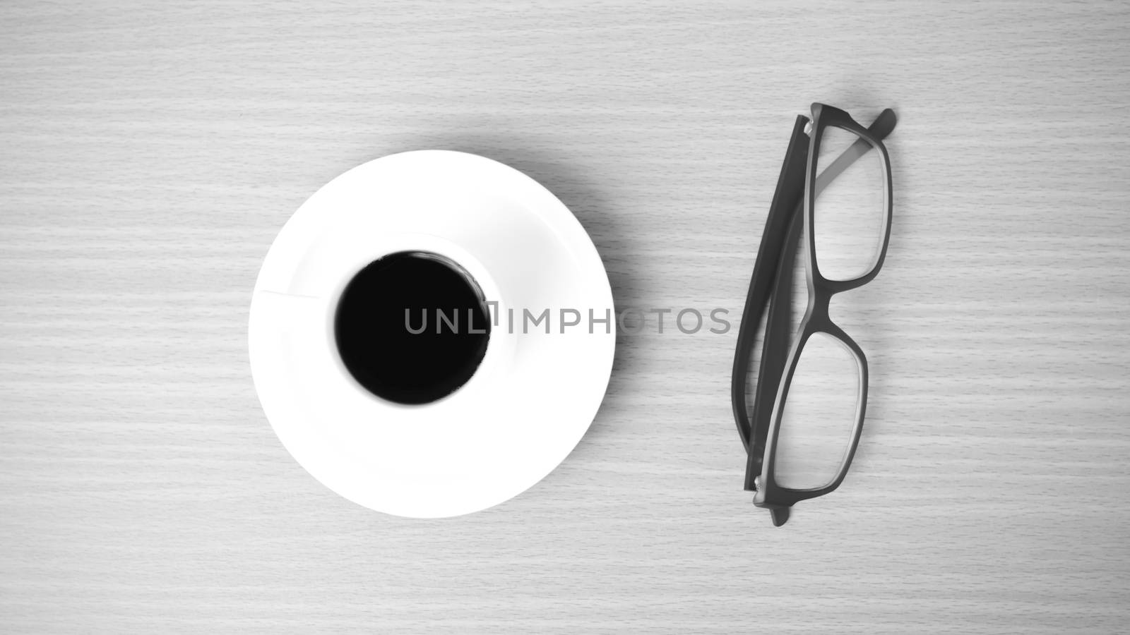 coffee cup and eyeglasses on wood background black and white color