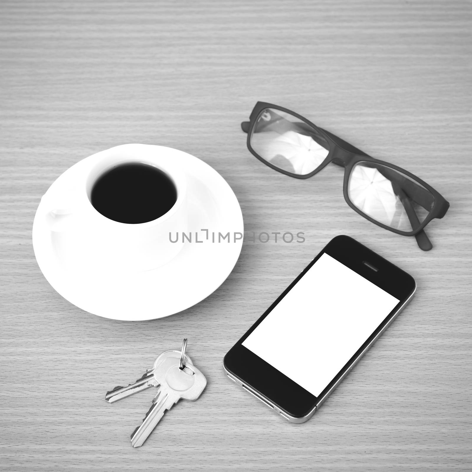 coffee cup and phone with key on wood background black and white color