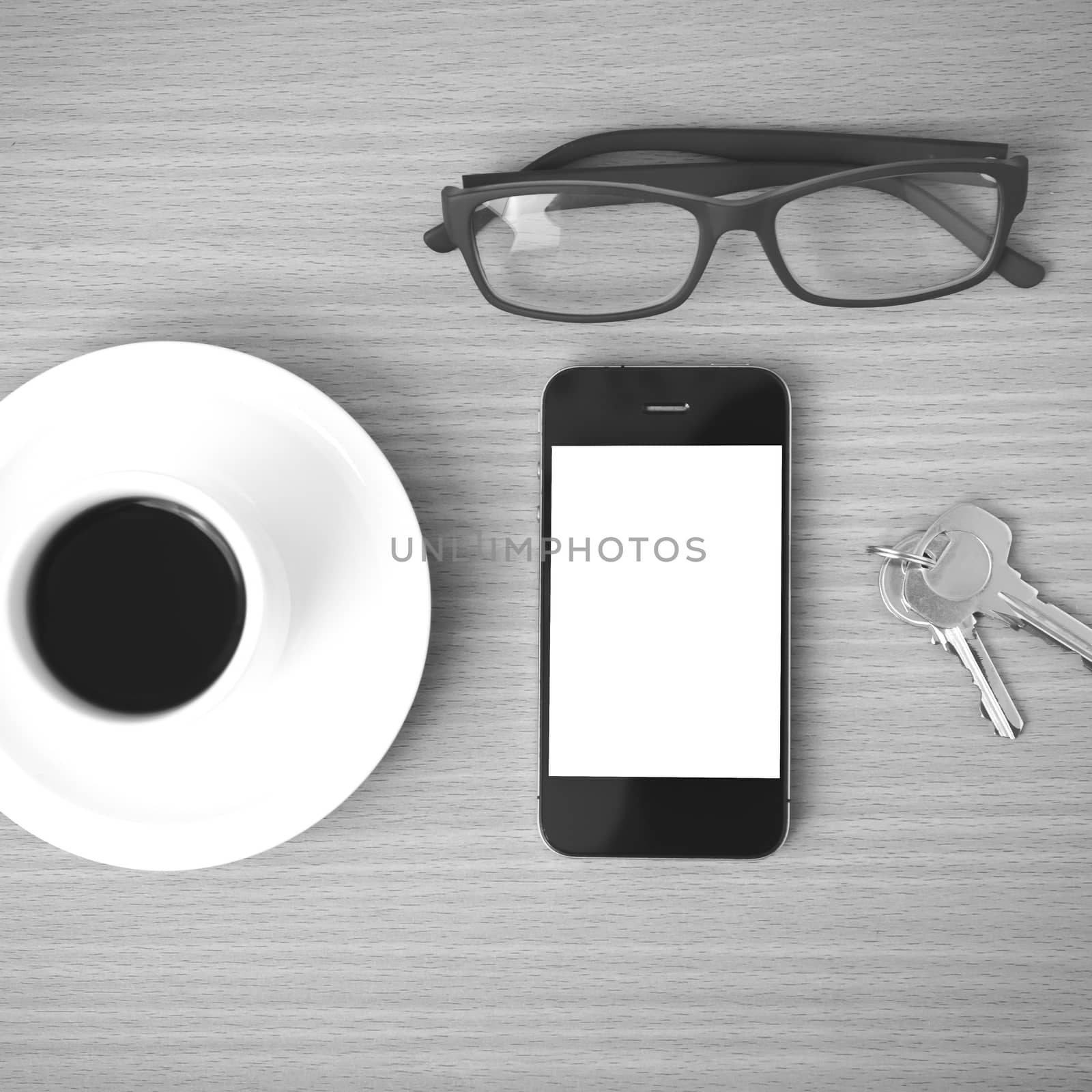 coffee cup and phone with key on wood background black and white color