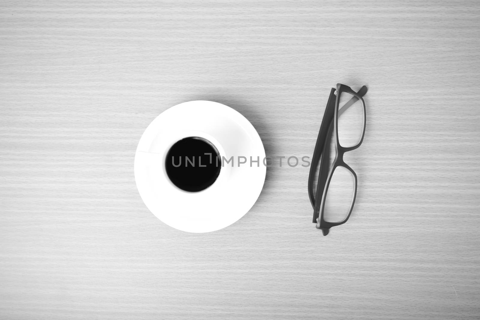 coffee cup and eyeglasses on wood background black and white color