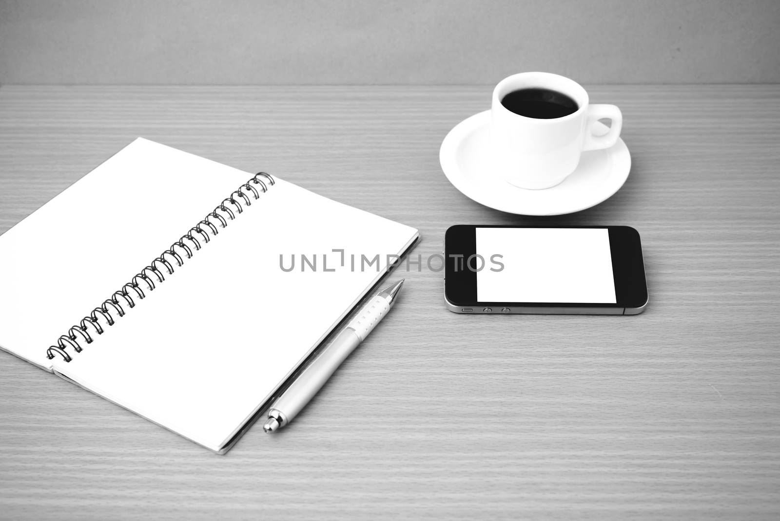 coffee cup and phone and notepad on wood background  black and white color