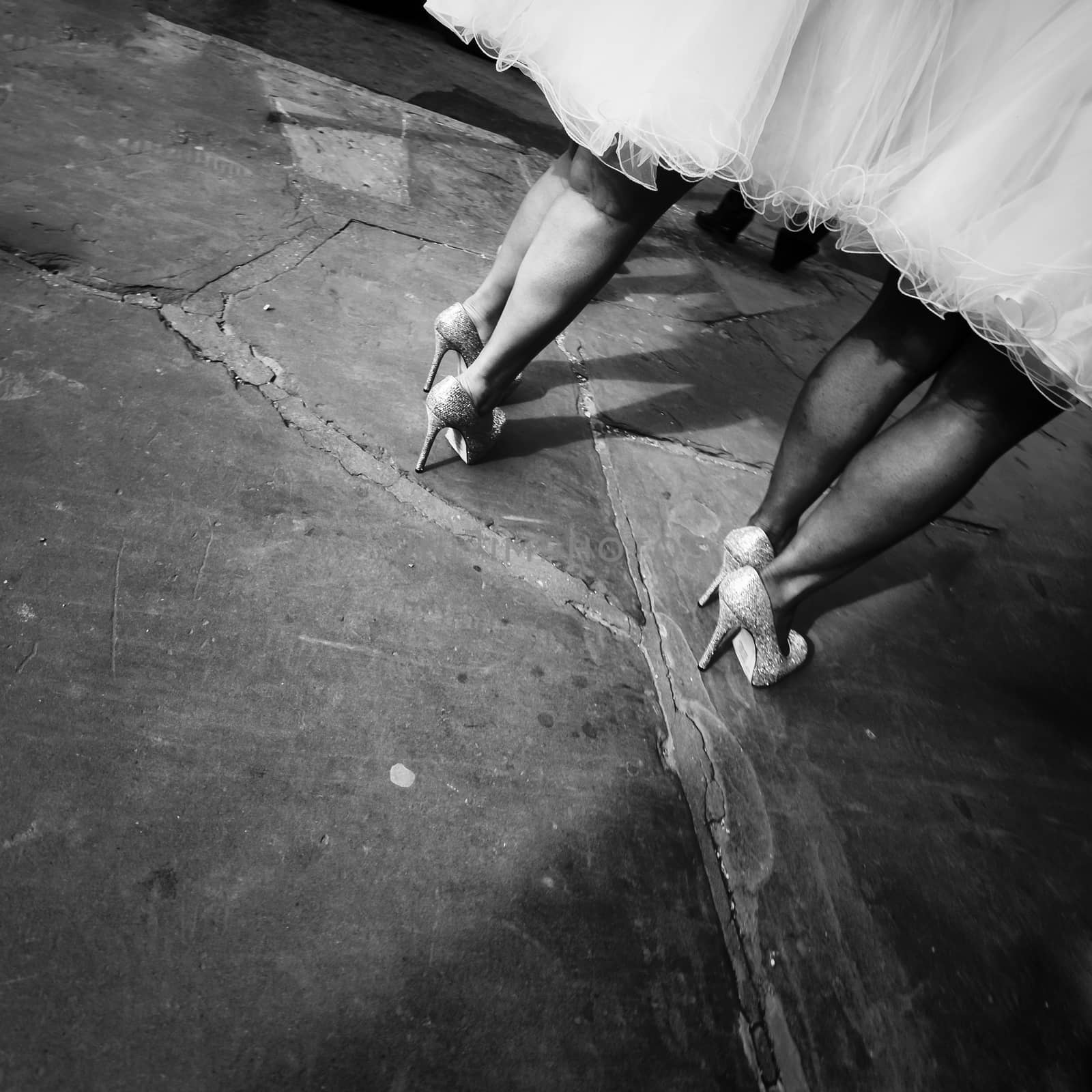 Two woman in wedding dresses standing on the sidewalk