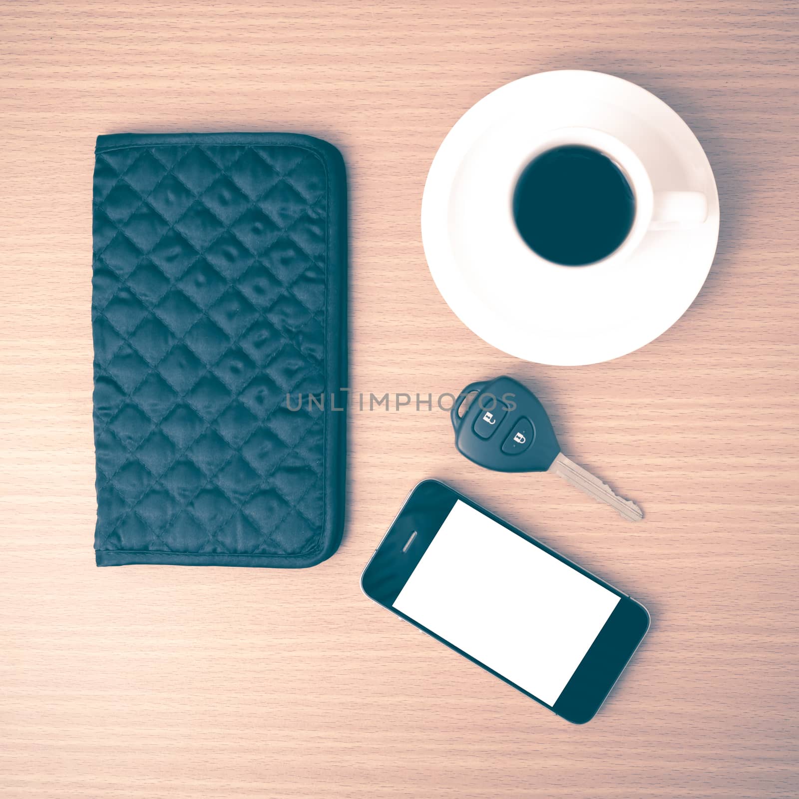 coffee cup with phone car key and wallet on wood background vintage style