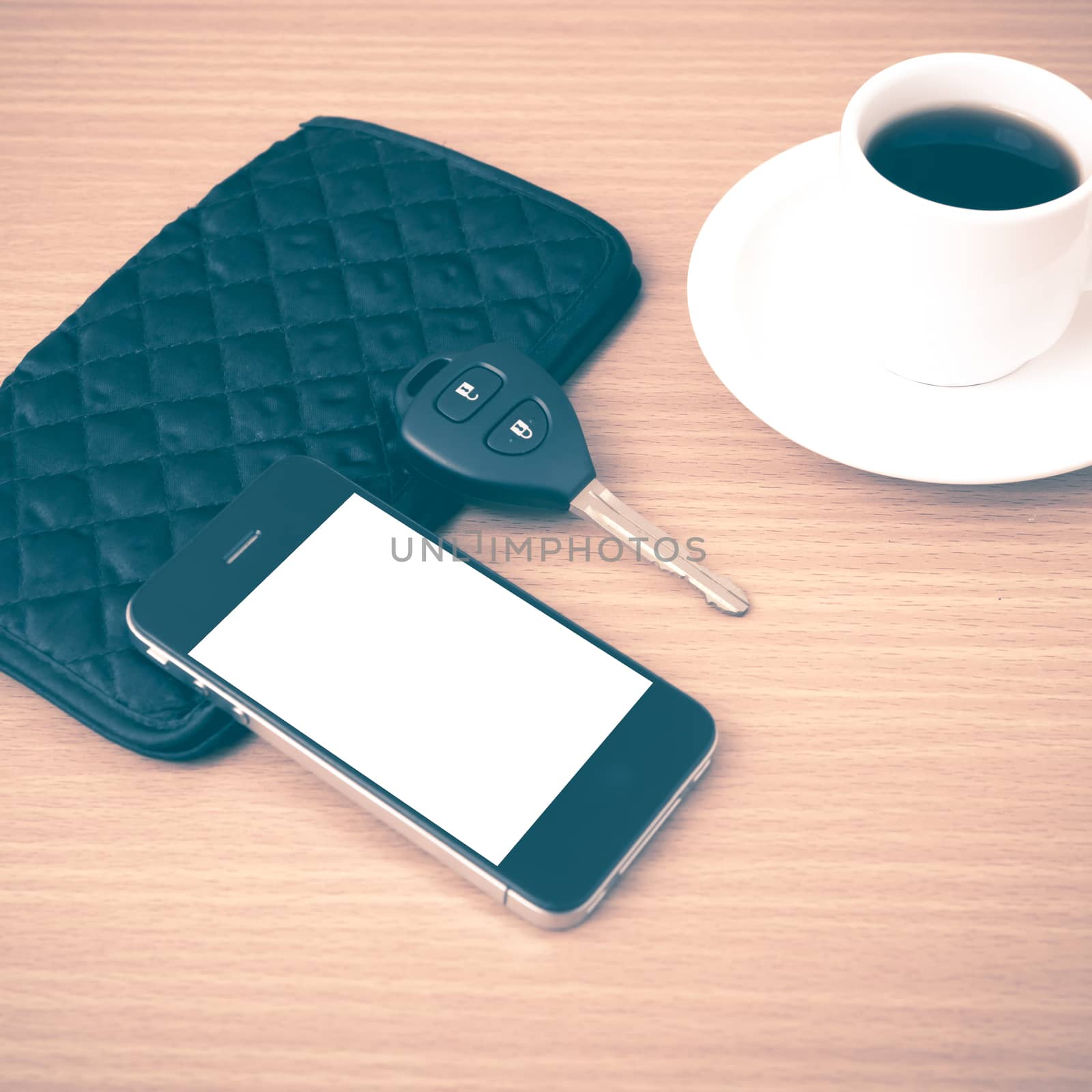 coffee cup with phone car key and wallet on wood background vintage style