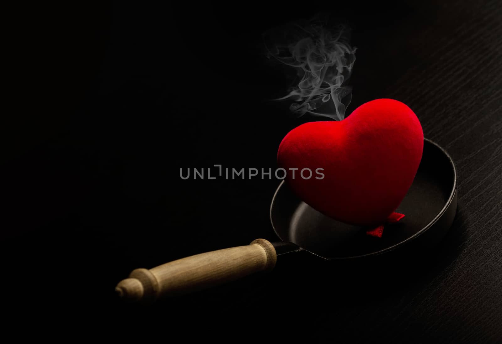 A red heart smoking on a metal frying pan