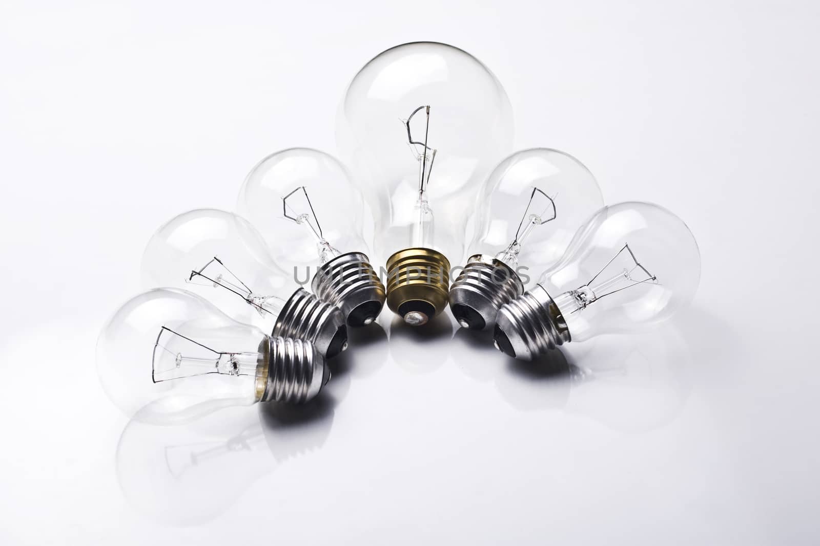 Composition with six light bulbs, one being bigger and having a golden fillet on white background