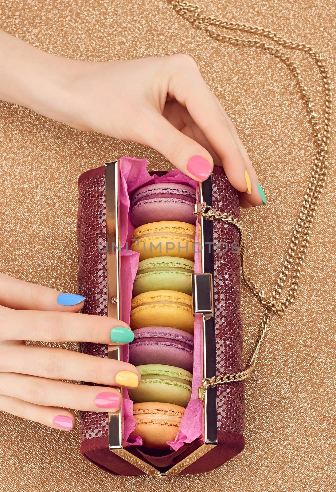 Macarons french in handbag, woman hands. Luxury shiny glamor fashion clutch. Sweet colorful dessert. Unusual creative art, gold party background, bokeh, copyspase. Vintage