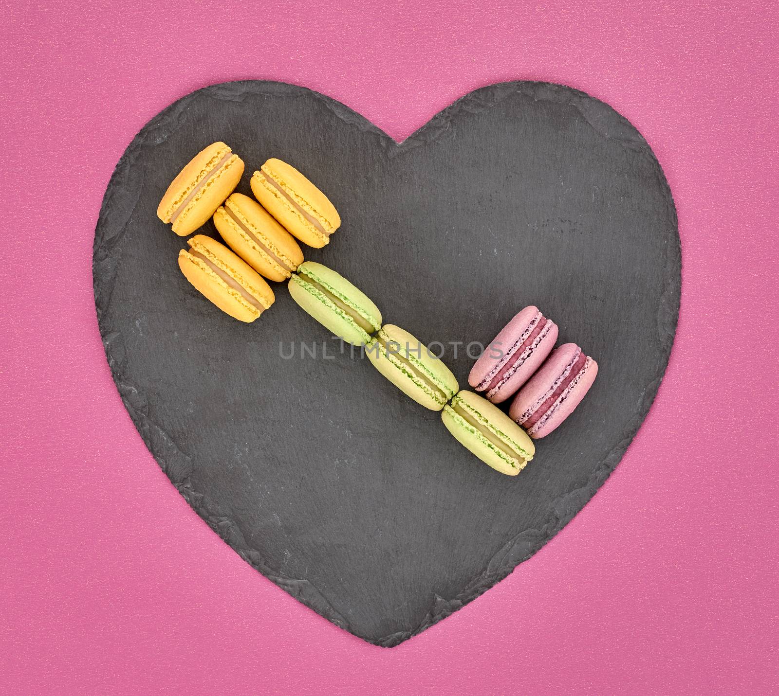 Still life, macarons sweet colorful, key shape, heart black placemat. French traditional delicious dessert. Unusual creative romantic, gray background. Concept for love story.Valentines Day