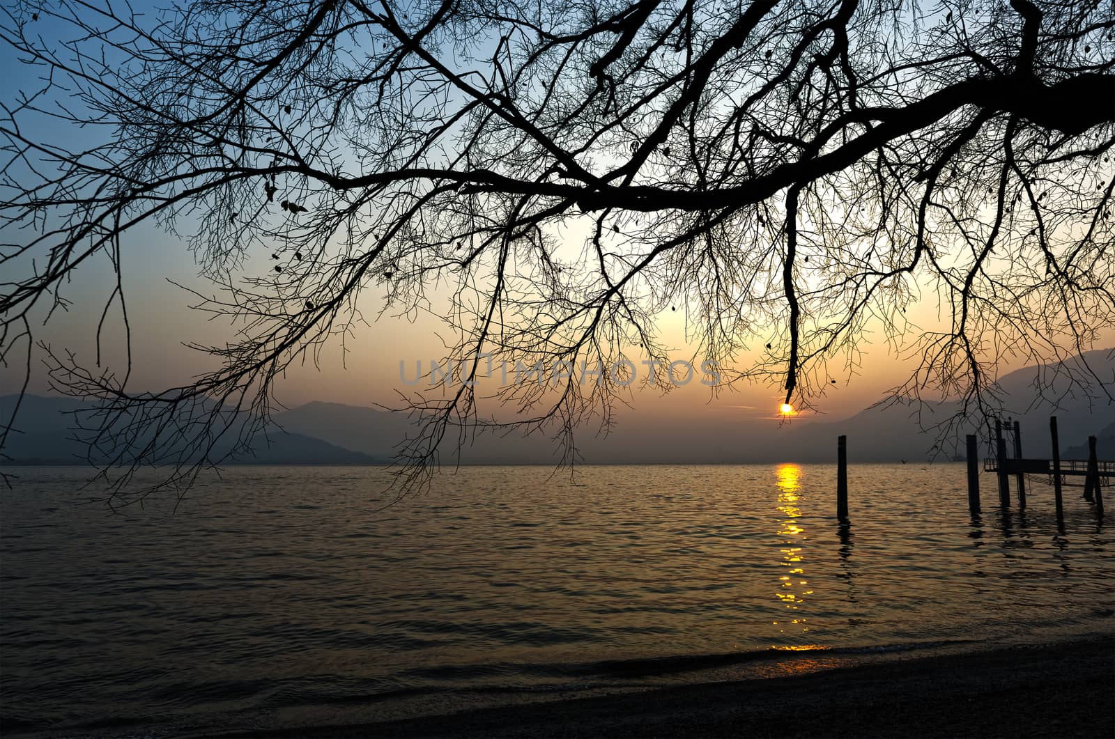 sunset over the lake major with the mists of the horizon and mountains in the background on a winter afternoon, Maccagno - Lombardy, Italy