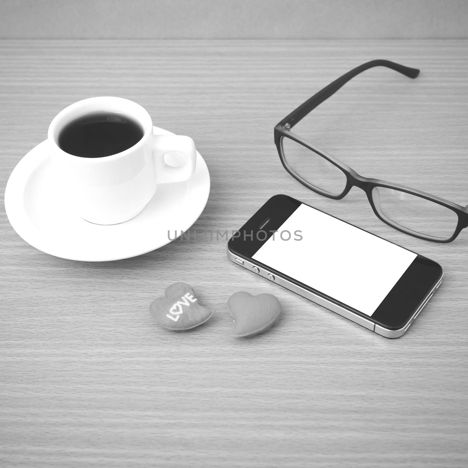 coffee,phone,eyeglasses and heart on wood table background black and white color