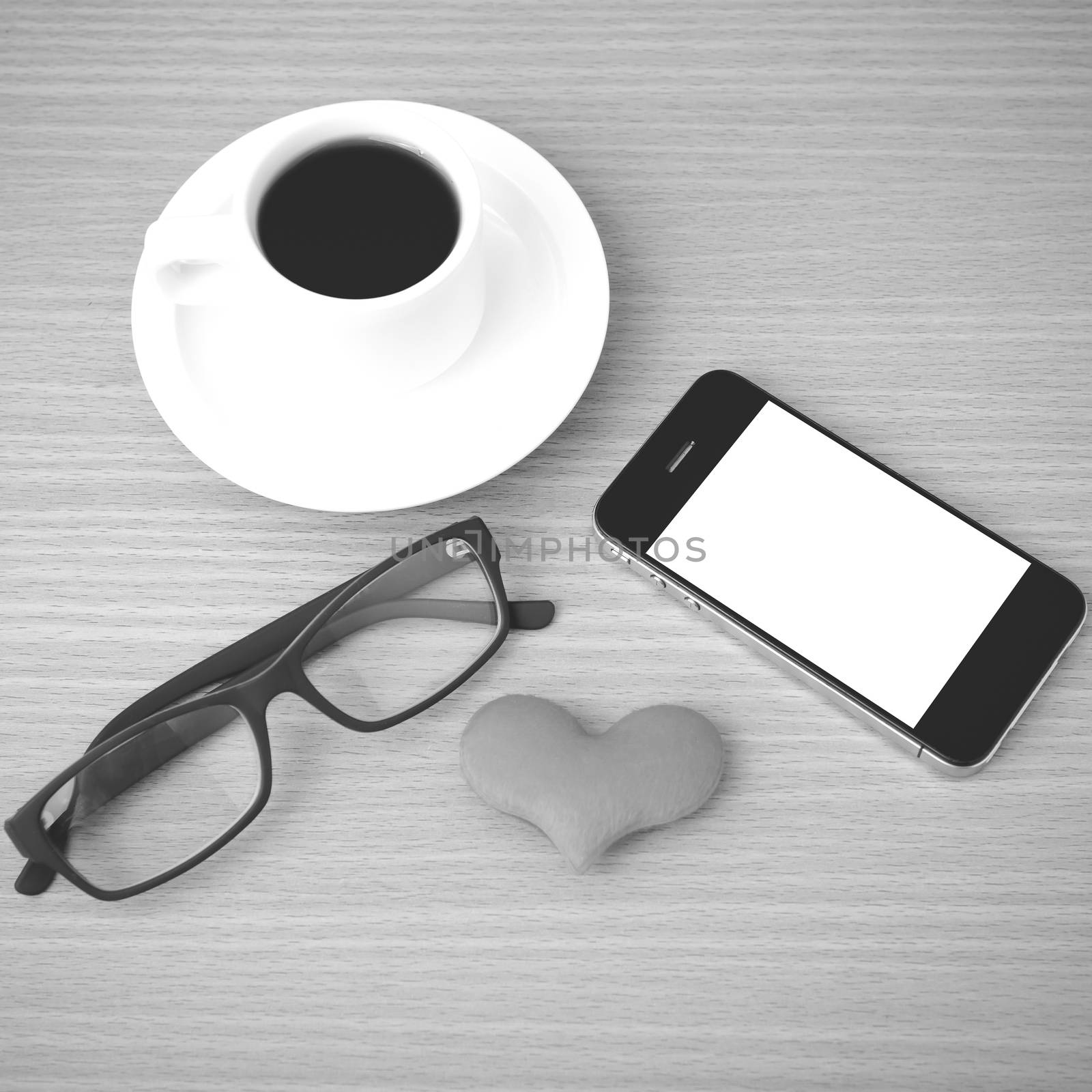 coffee,phone,eyeglasses and heart on wood table background black and white color