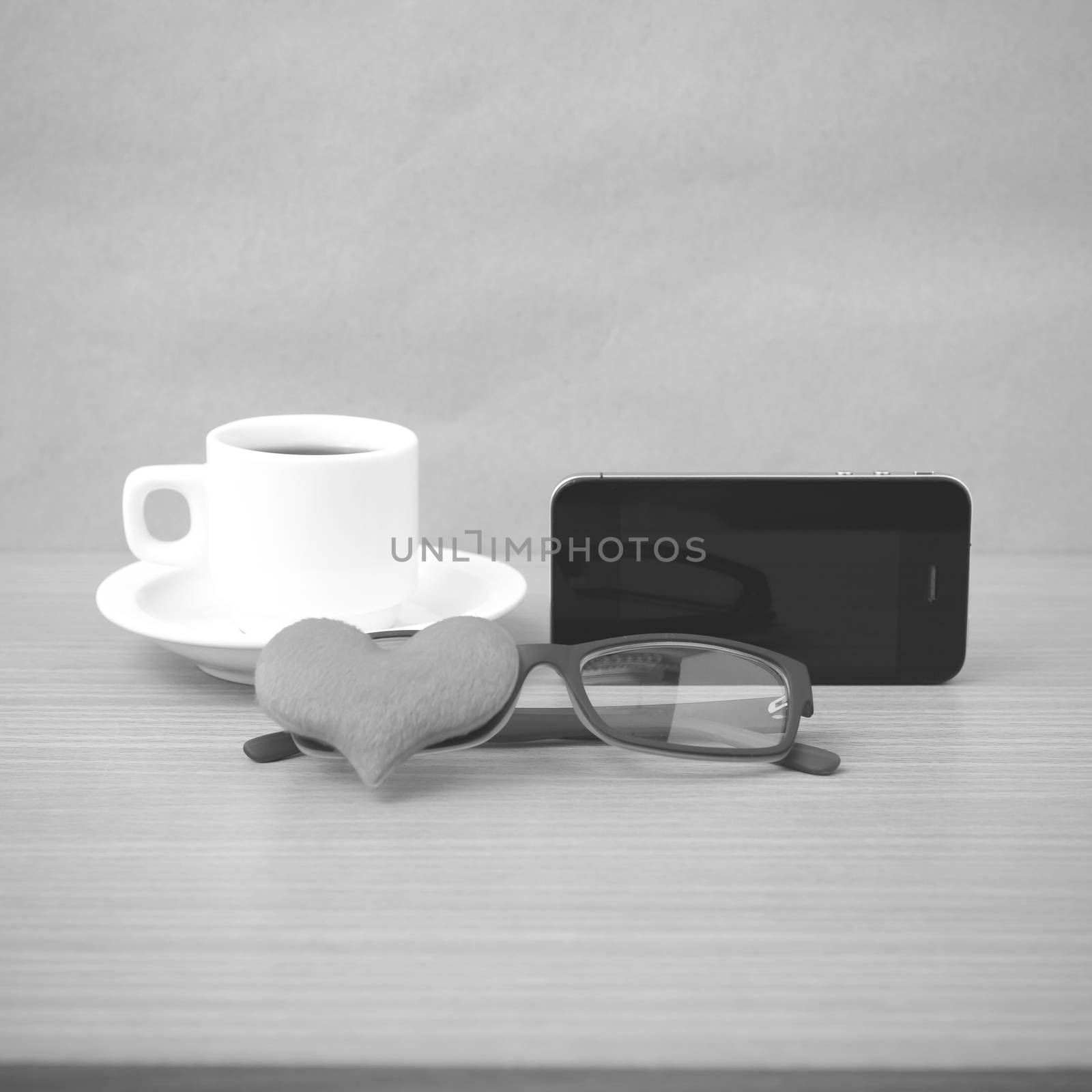 coffee,phone,eyeglasses and heart on wood table background black and white color