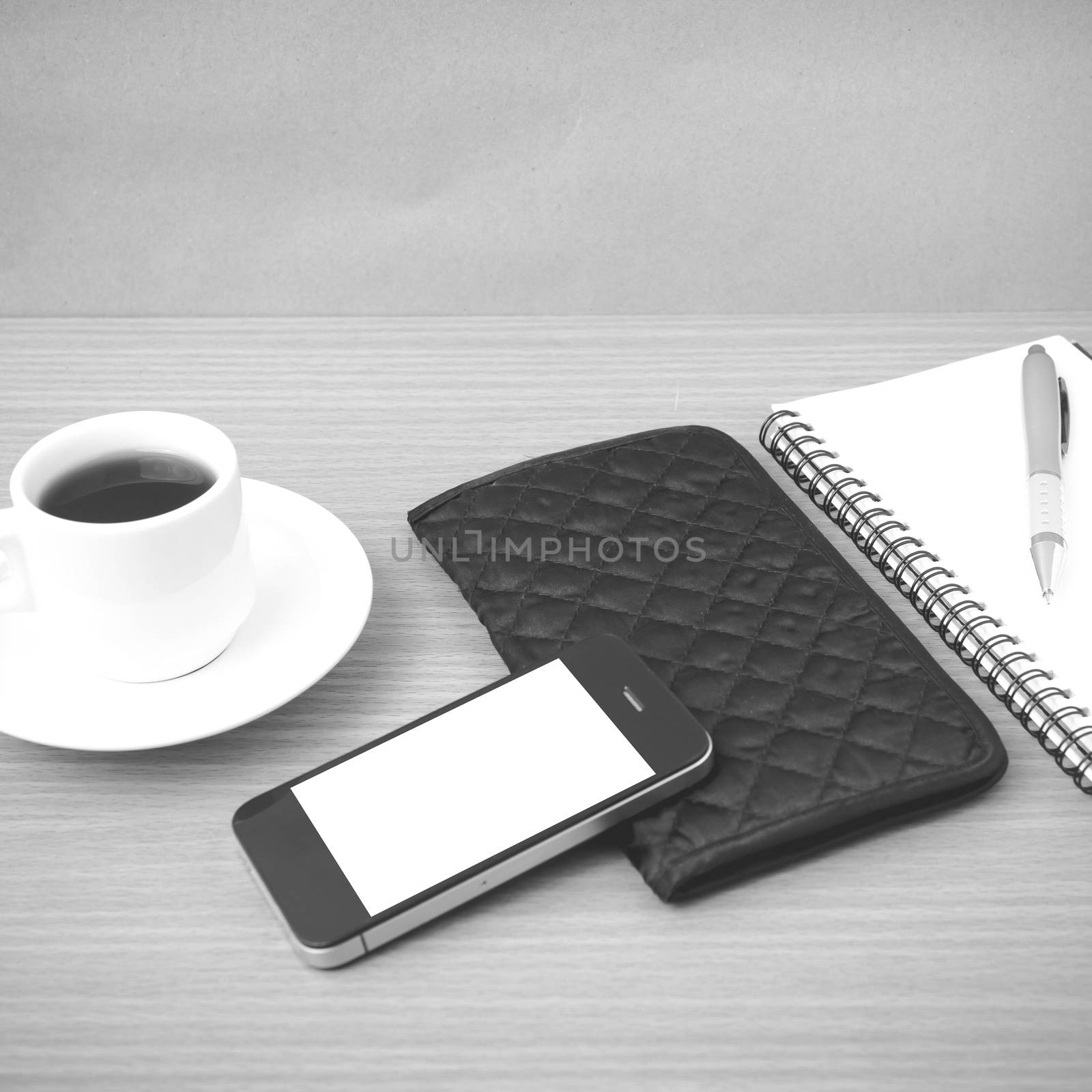 coffee,phone,notepad and wallet on wood table background black and white color