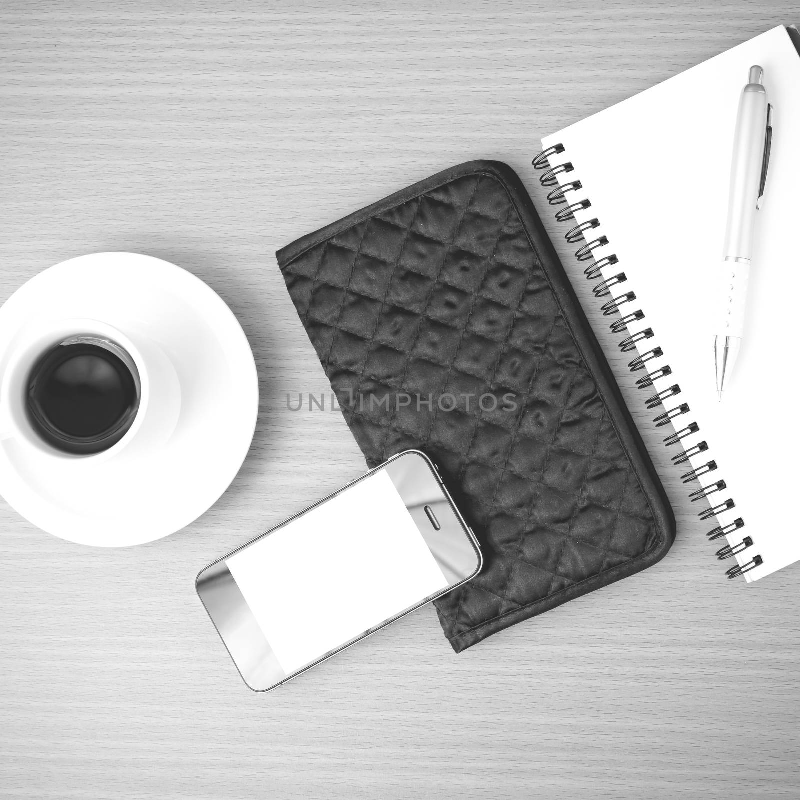 coffee,phone,notepad and wallet on wood table background black and white color