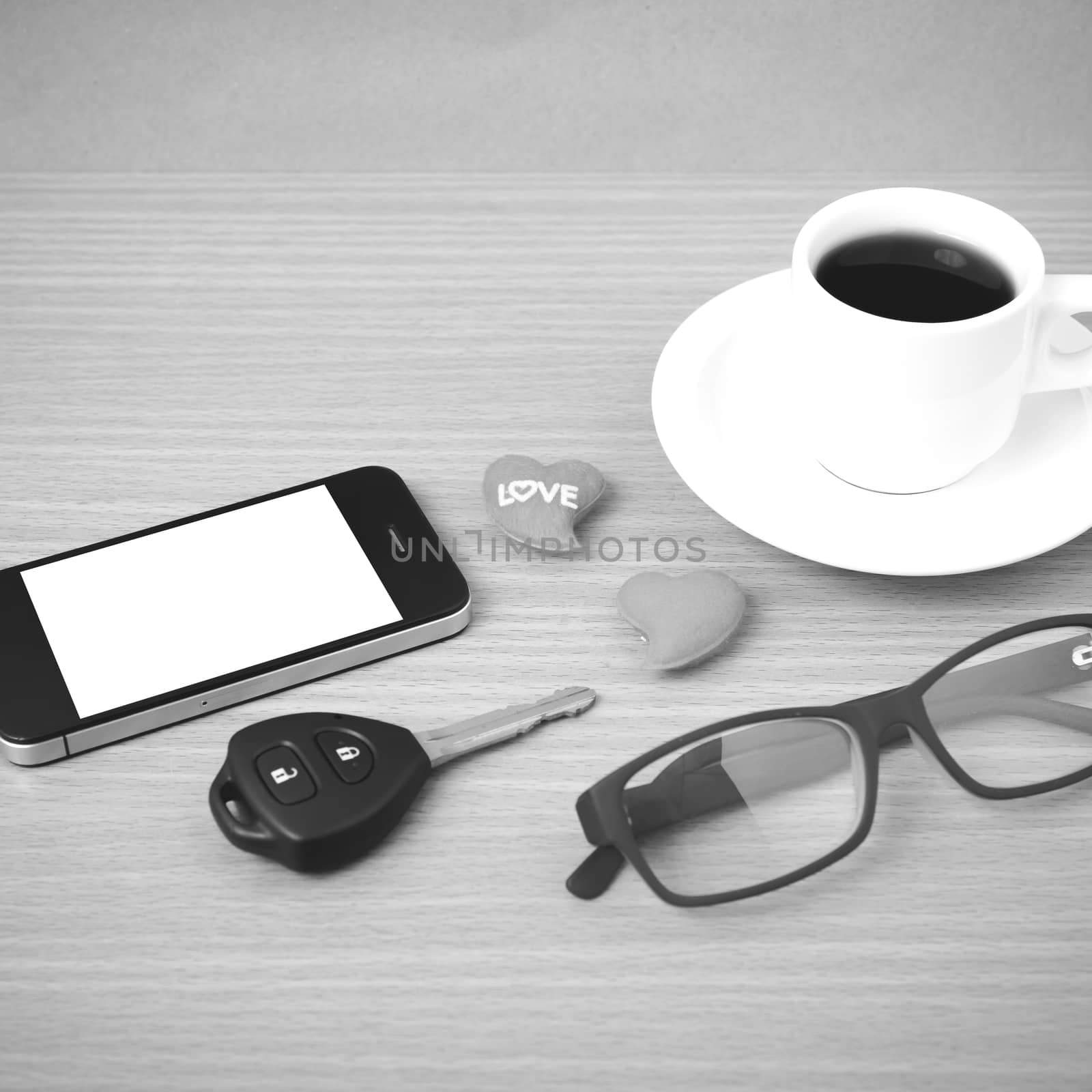 coffee,phone,eyeglasses,car key and heart on wood table background black  and white color