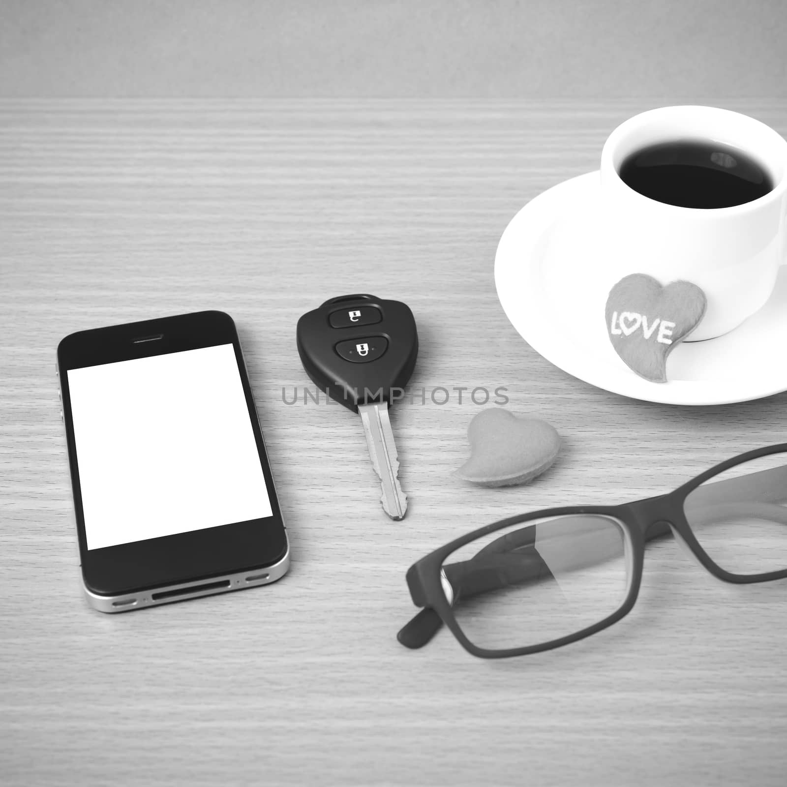 coffee,phone,eyeglasses,car key and heart on wood table background black  and white color