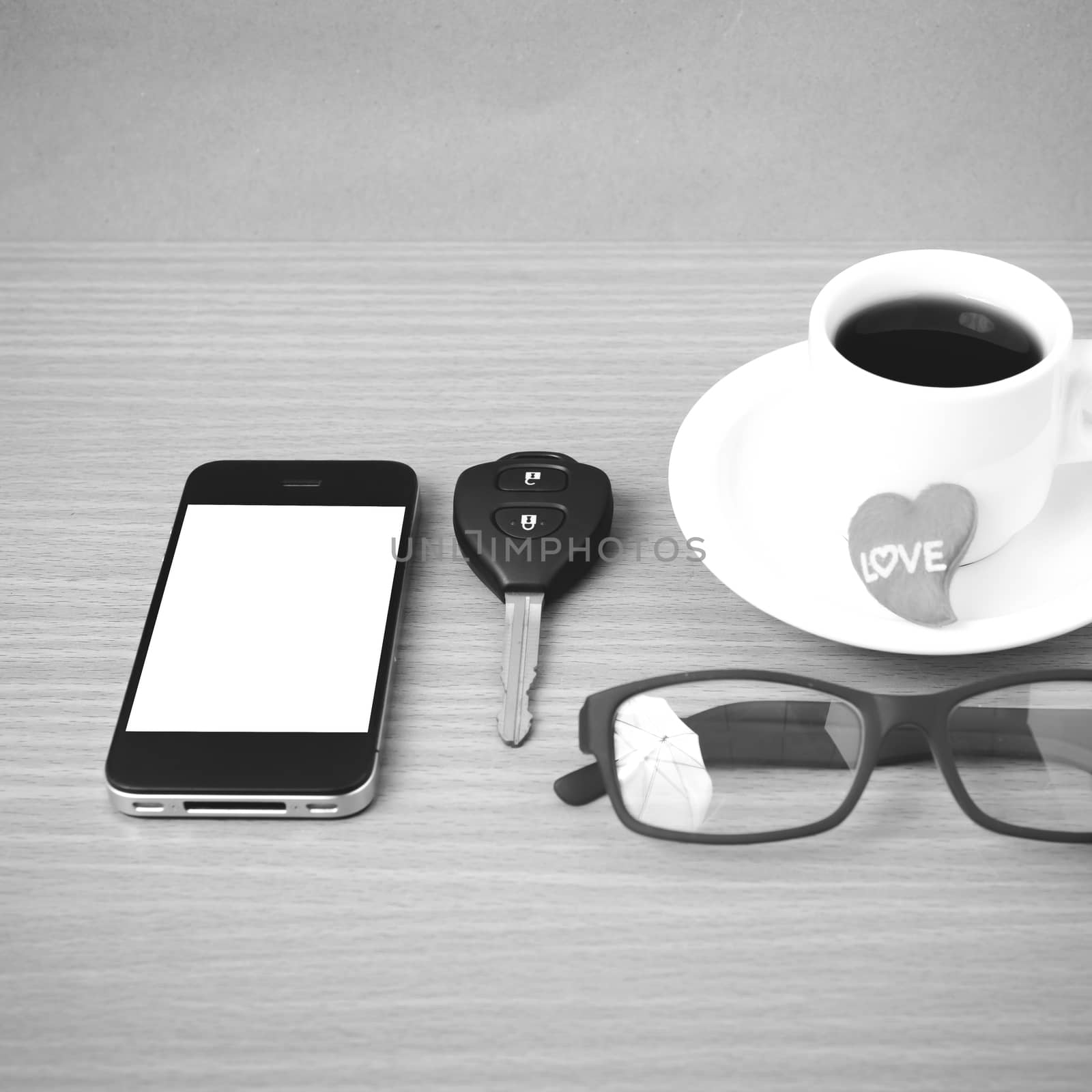 coffee,phone,eyeglasses,car key and heart on wood table background black  and white color