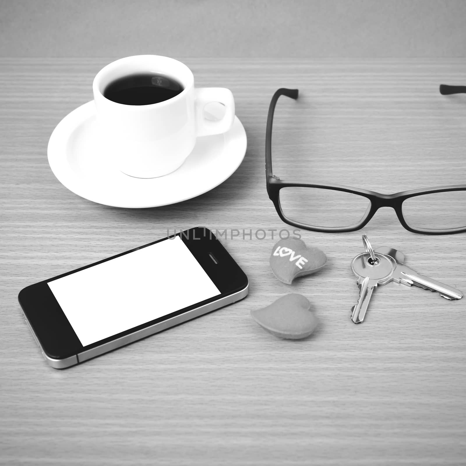 coffee,phone,eyeglasses,key and heart on wood table background black  and white color