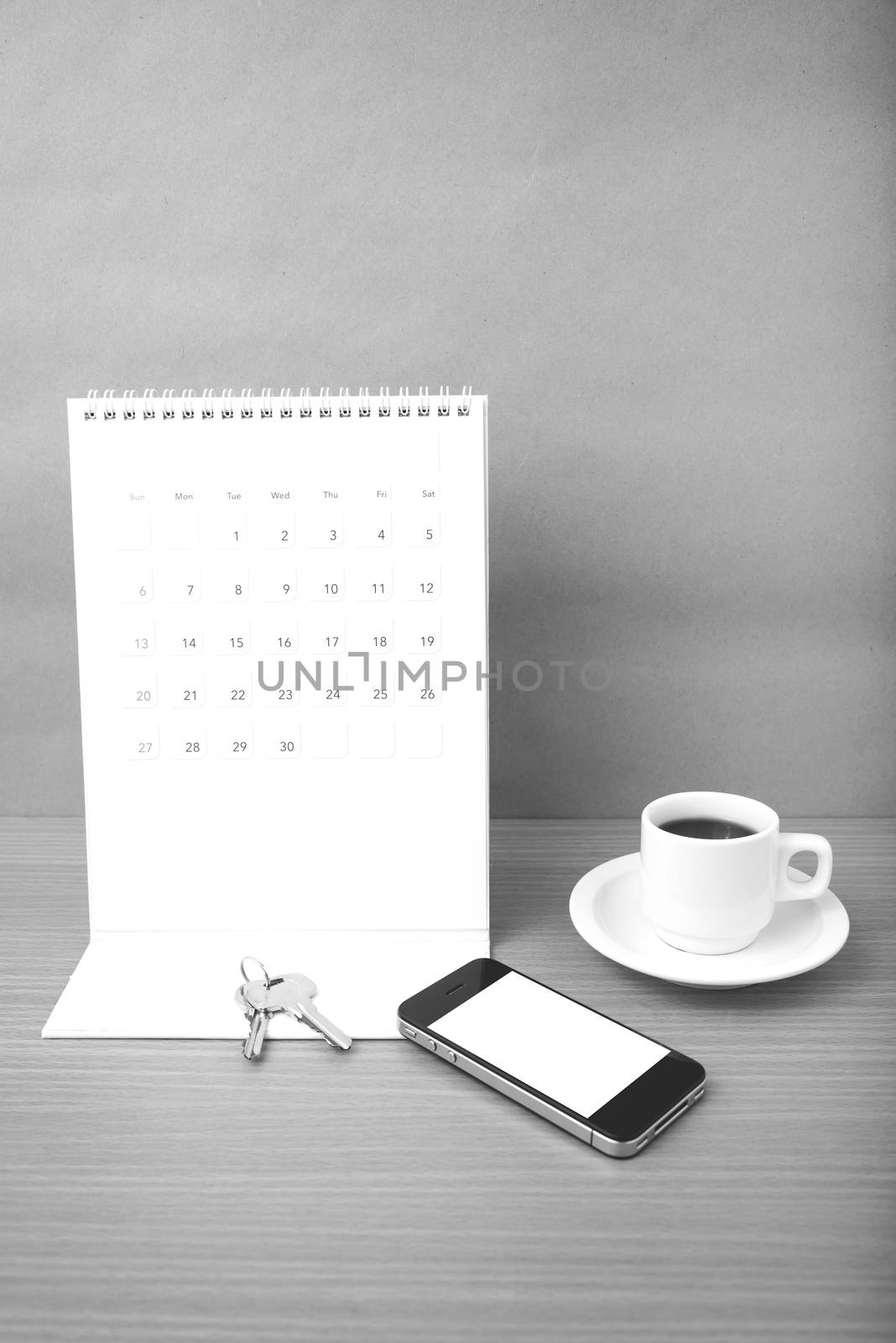 coffee,phone,key and calendar on wood table background black and white color