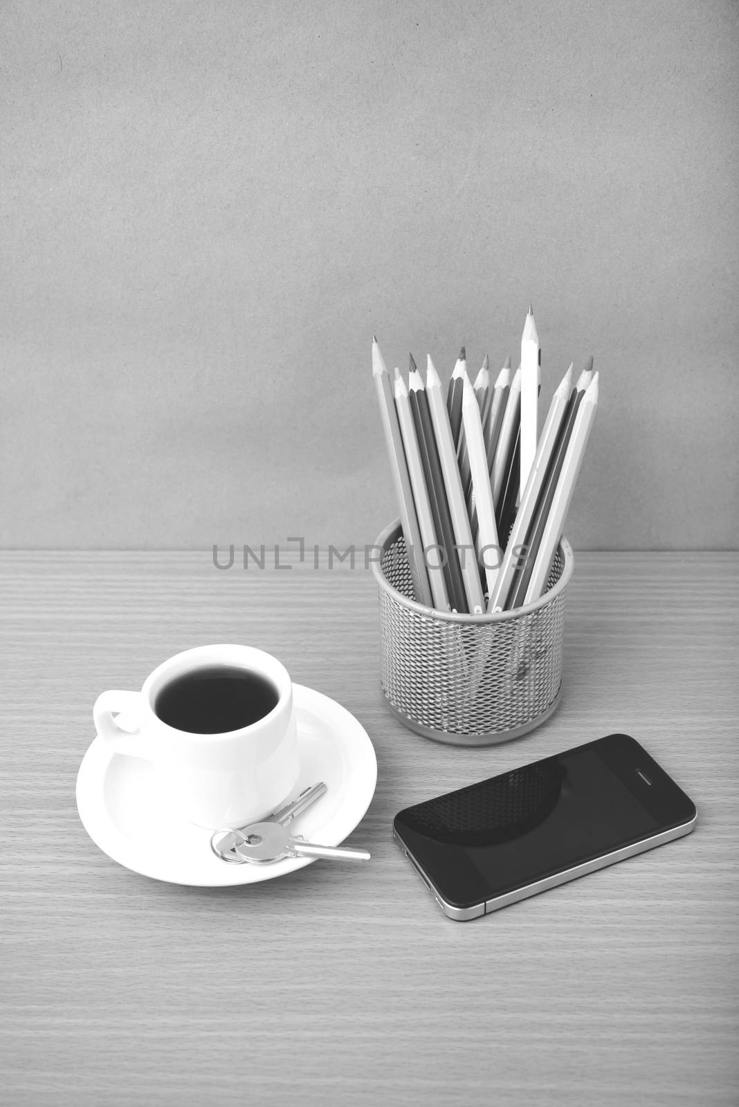 coffee,phone,key and pencil on wood table background black and white color