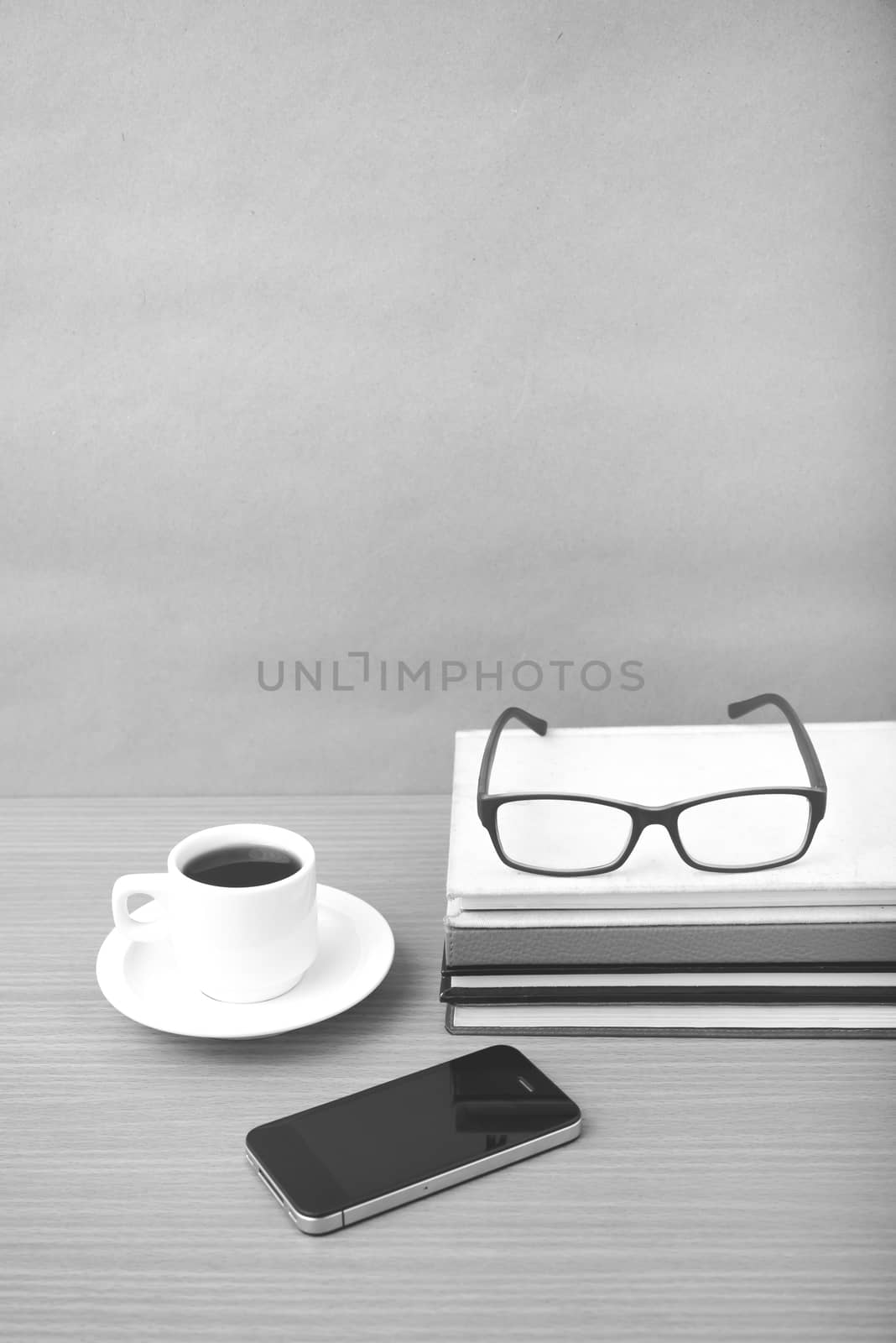 coffee,phone,stack of book and eyeglasses on wood table background black and white color