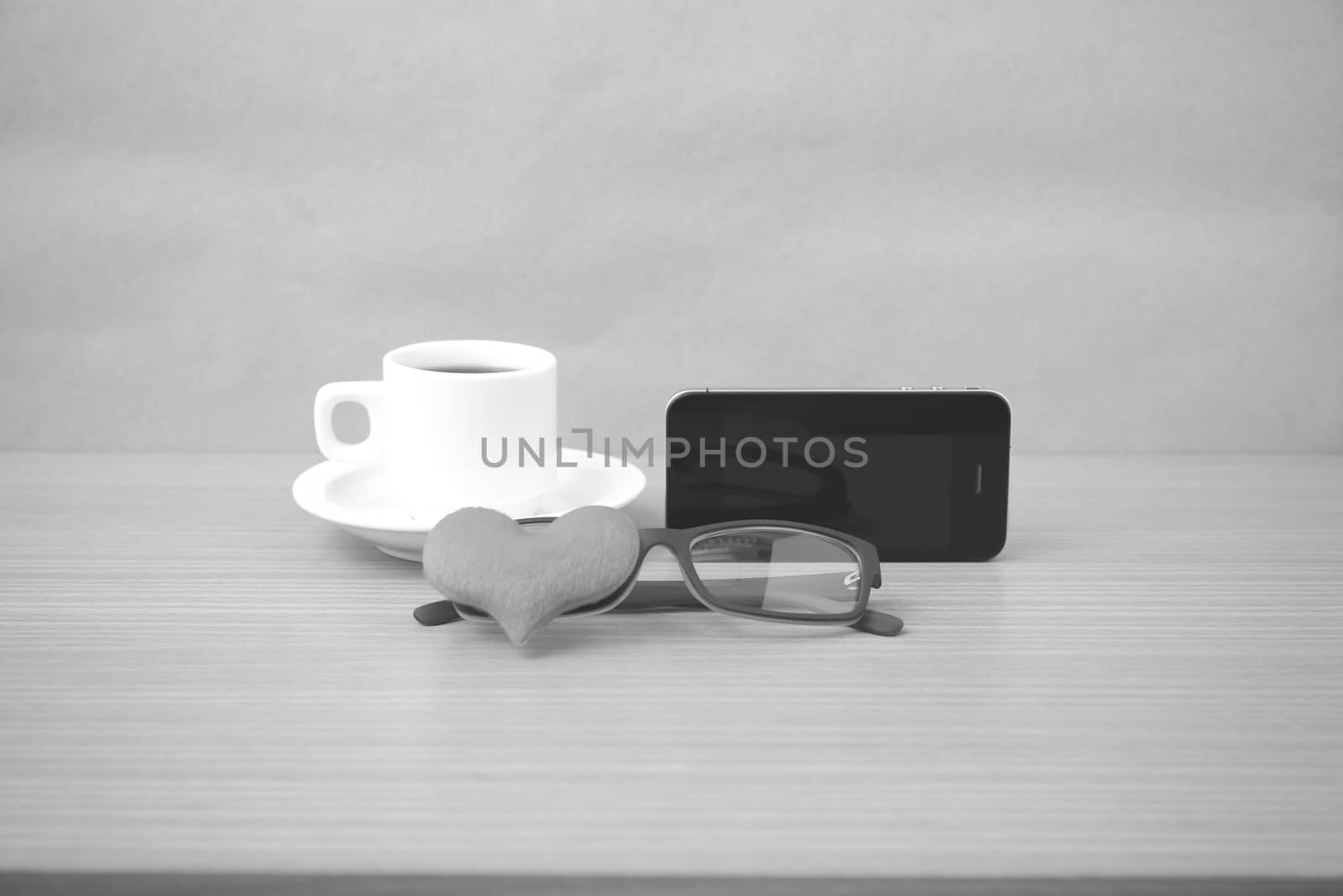 coffee,phone,eyeglasses and heart on wood table background black and white color
