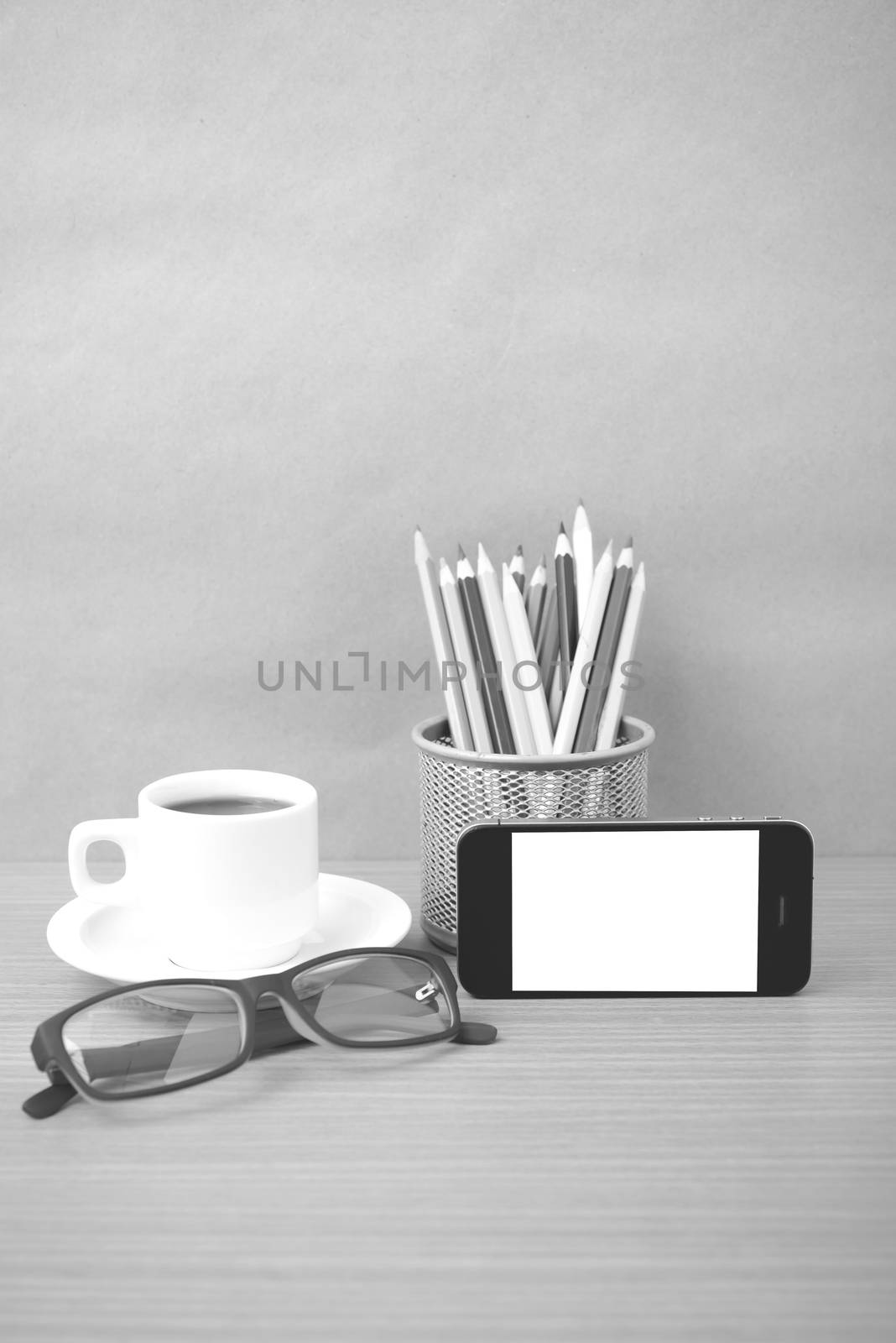 coffee,phone,eyeglasses and pencil on wood table background black and white color