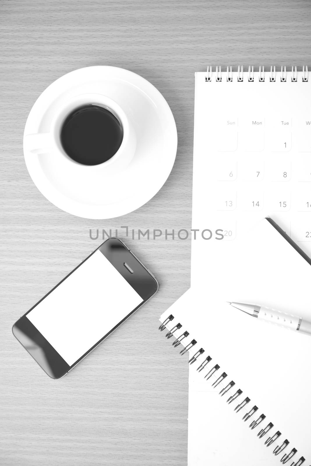 coffee,phone,notepad and calendar on wood table background black and white color