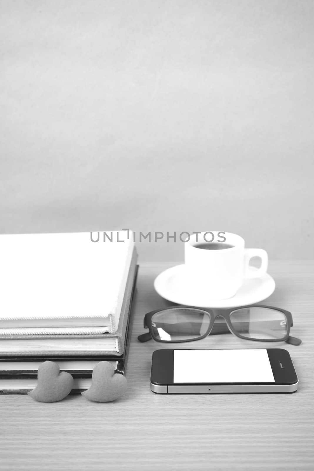 coffee,phone,eyeglasses,stack of book and heart on wood table background black  and white color