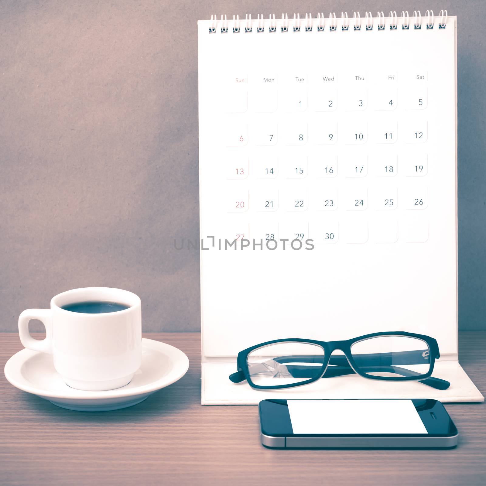 coffee,phone,eyeglasses and calendar on wood table background vintage style