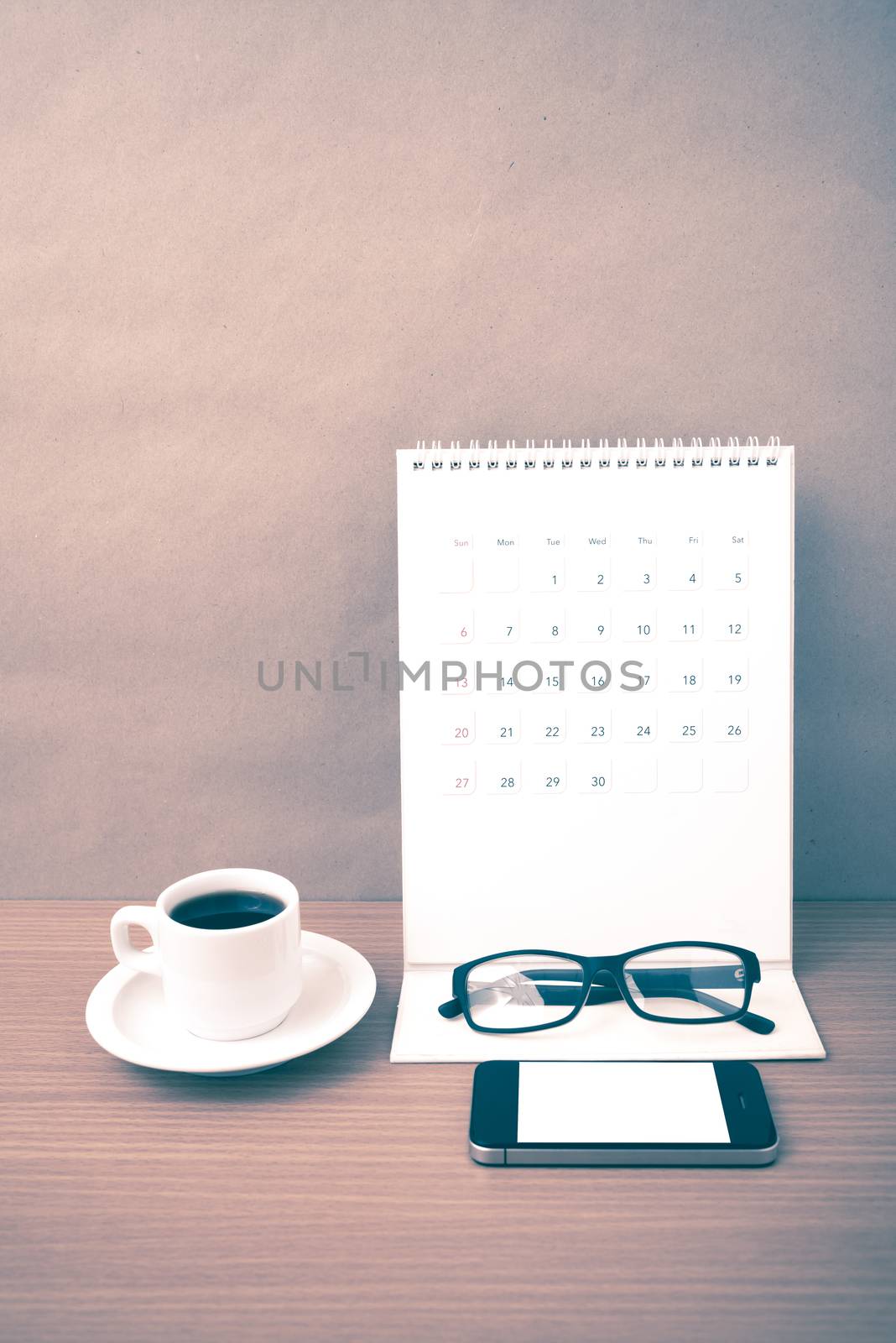 coffee,phone,eyeglasses and calendar on wood table background vintage style