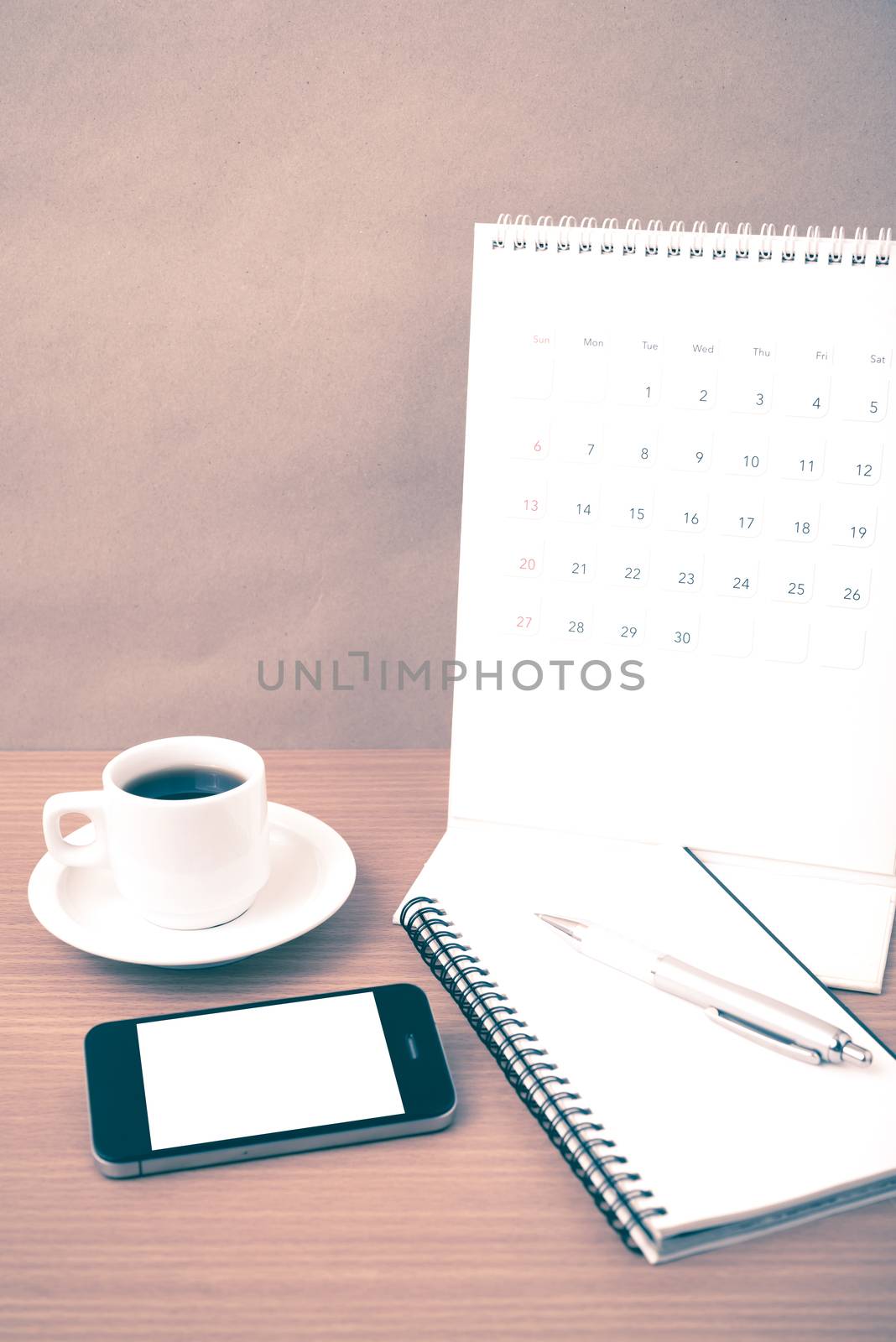 coffee,phone,notepad and calendar on wood table background vintage style